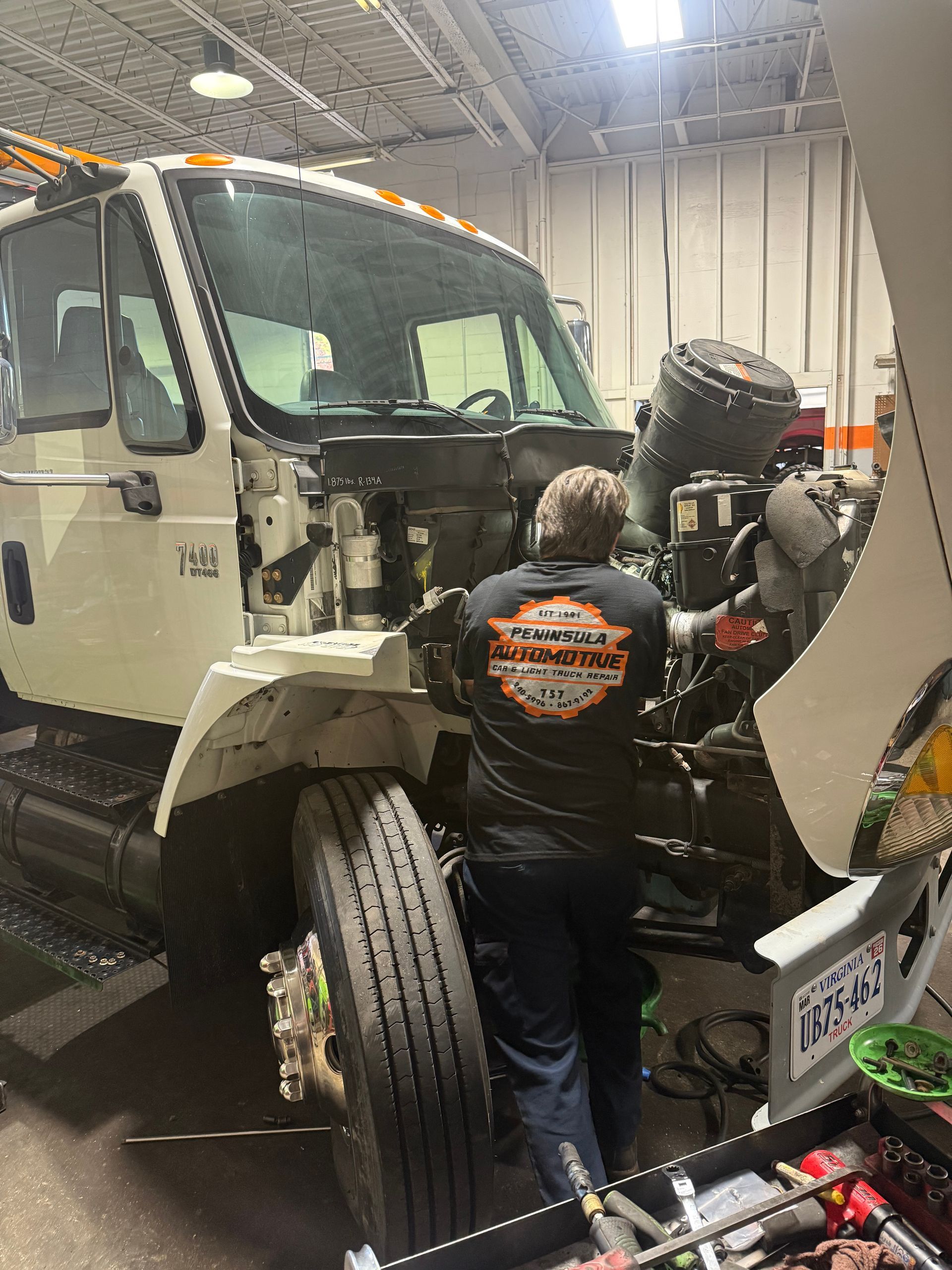 Tow truck in a garage with a mechanic working near the front wheel