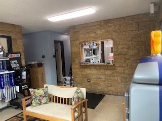 Interior of a waiting area with a bench, brick wall, service window, and display shelves.