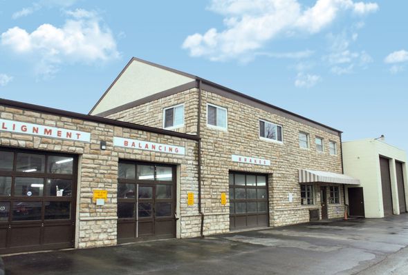 Auto repair shop with brown brick facade, bay doors, and signs reading 