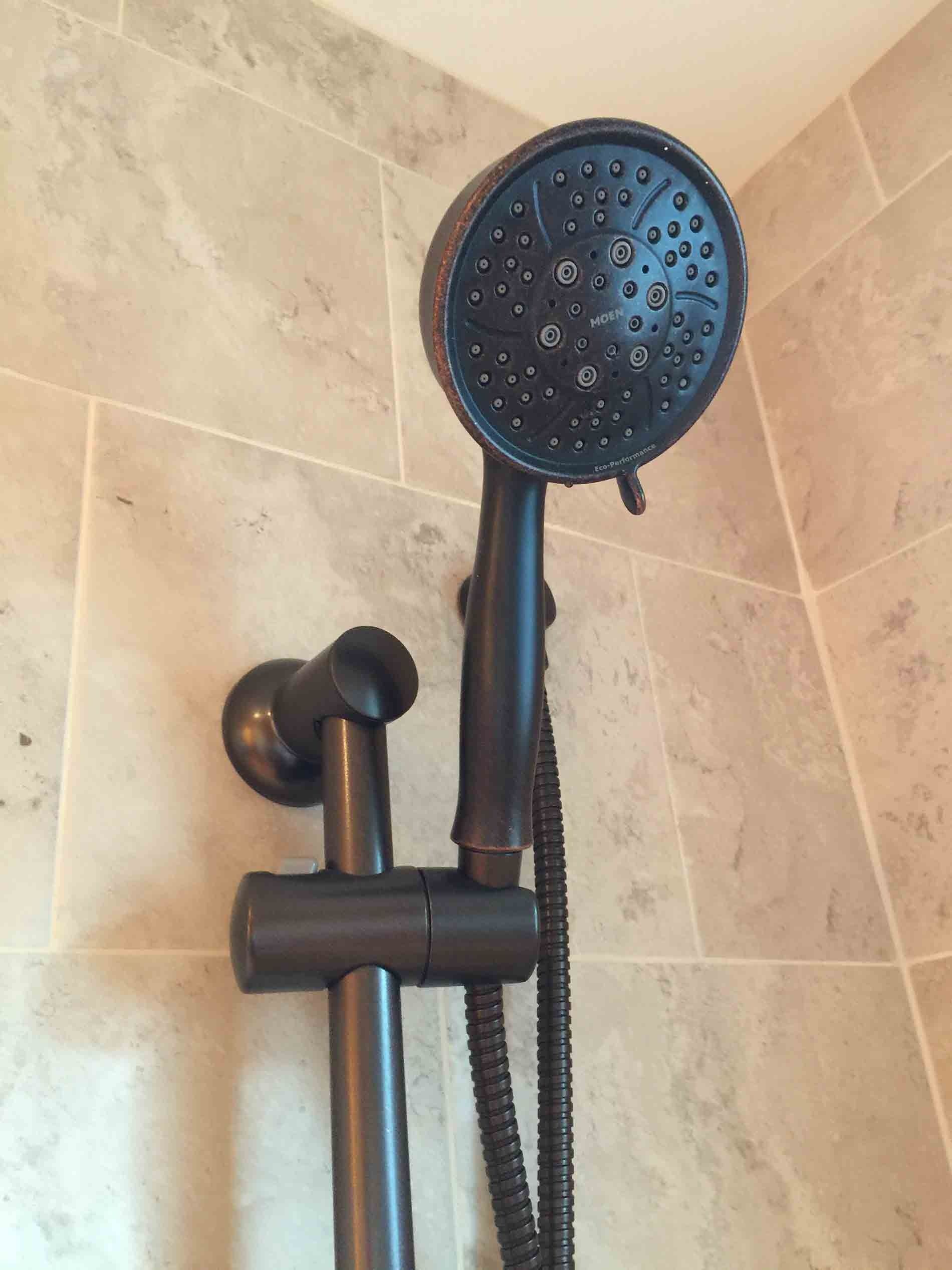A black shower head with a hose attached to it