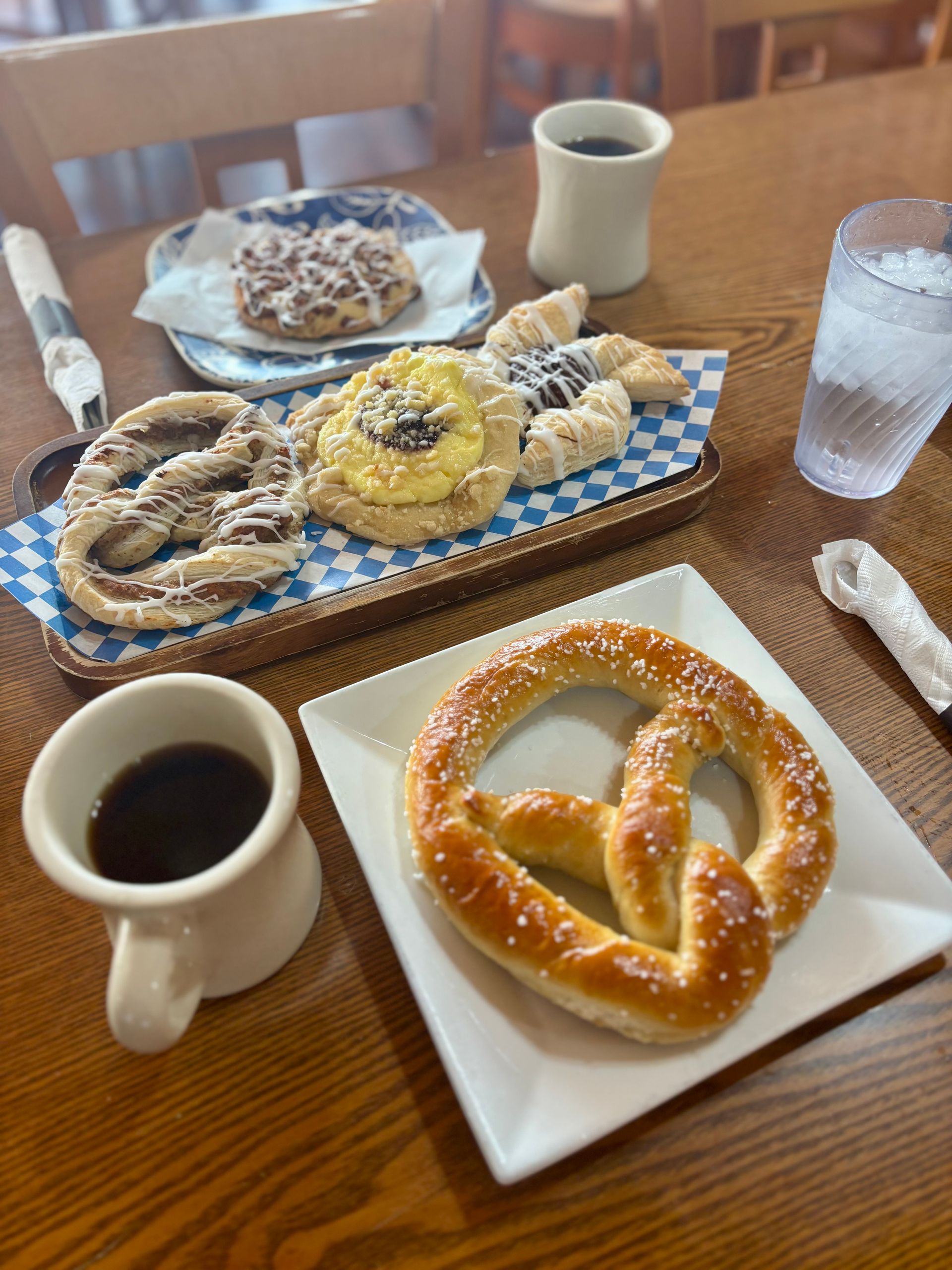Pretzels and cookies with two cups of coffee on a wooden table at a cafe
