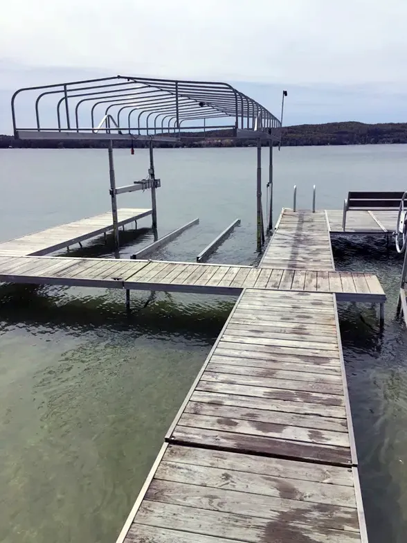 Wooden dock with a covered boat lift over calm water under a cloudy sky