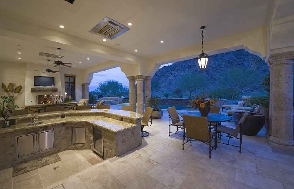 A large patio with a table and chairs and a kitchen.
