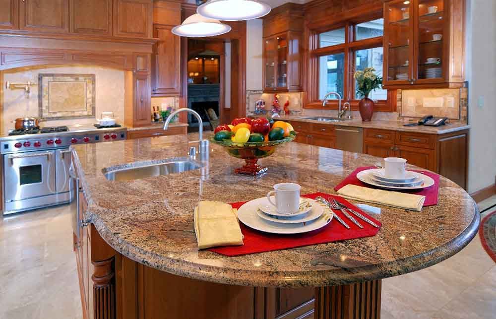 A kitchen with a granite counter top and a bowl of fruit on it