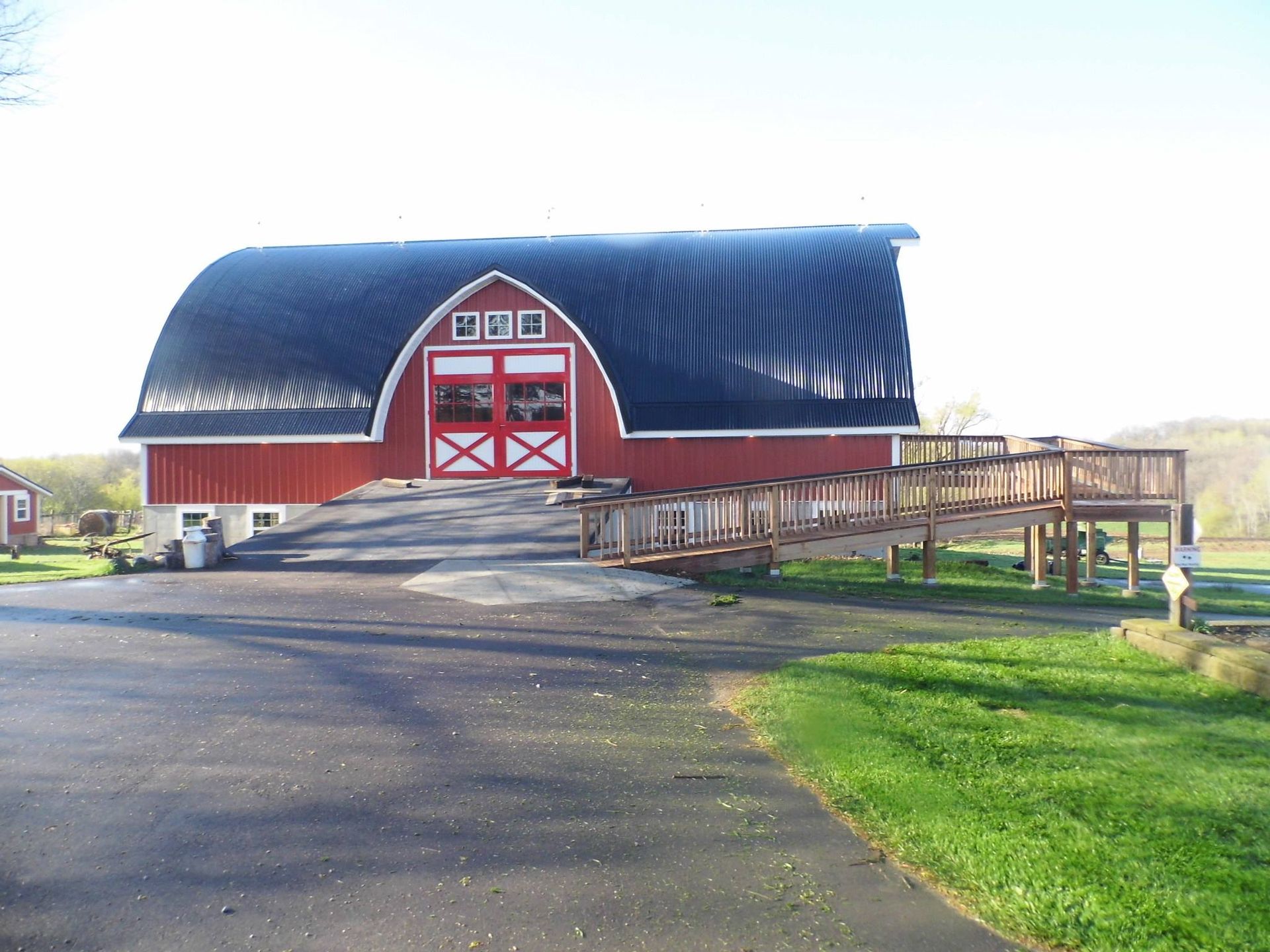 A red barn with a black roof and a ramp