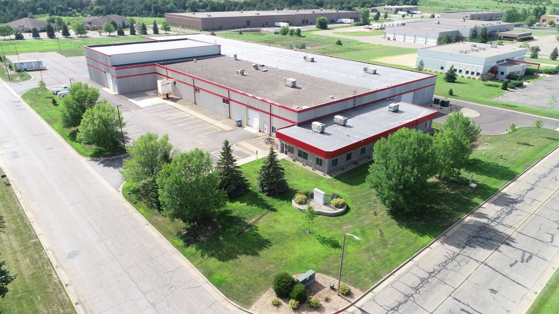 An aerial view of a large industrial building surrounded by trees and grass.