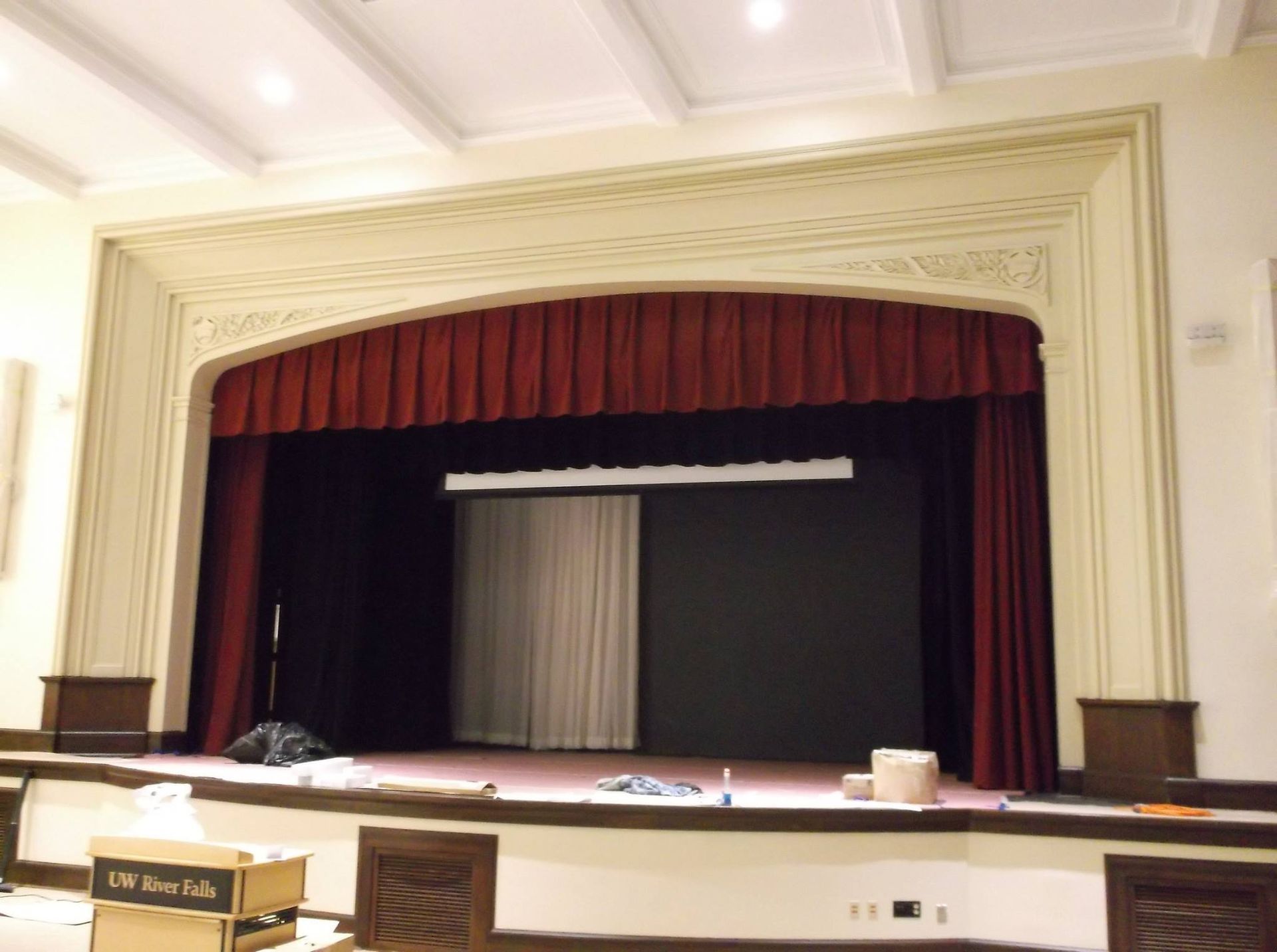 An empty auditorium with a red curtain and a box that says ' uc san diego ' on it