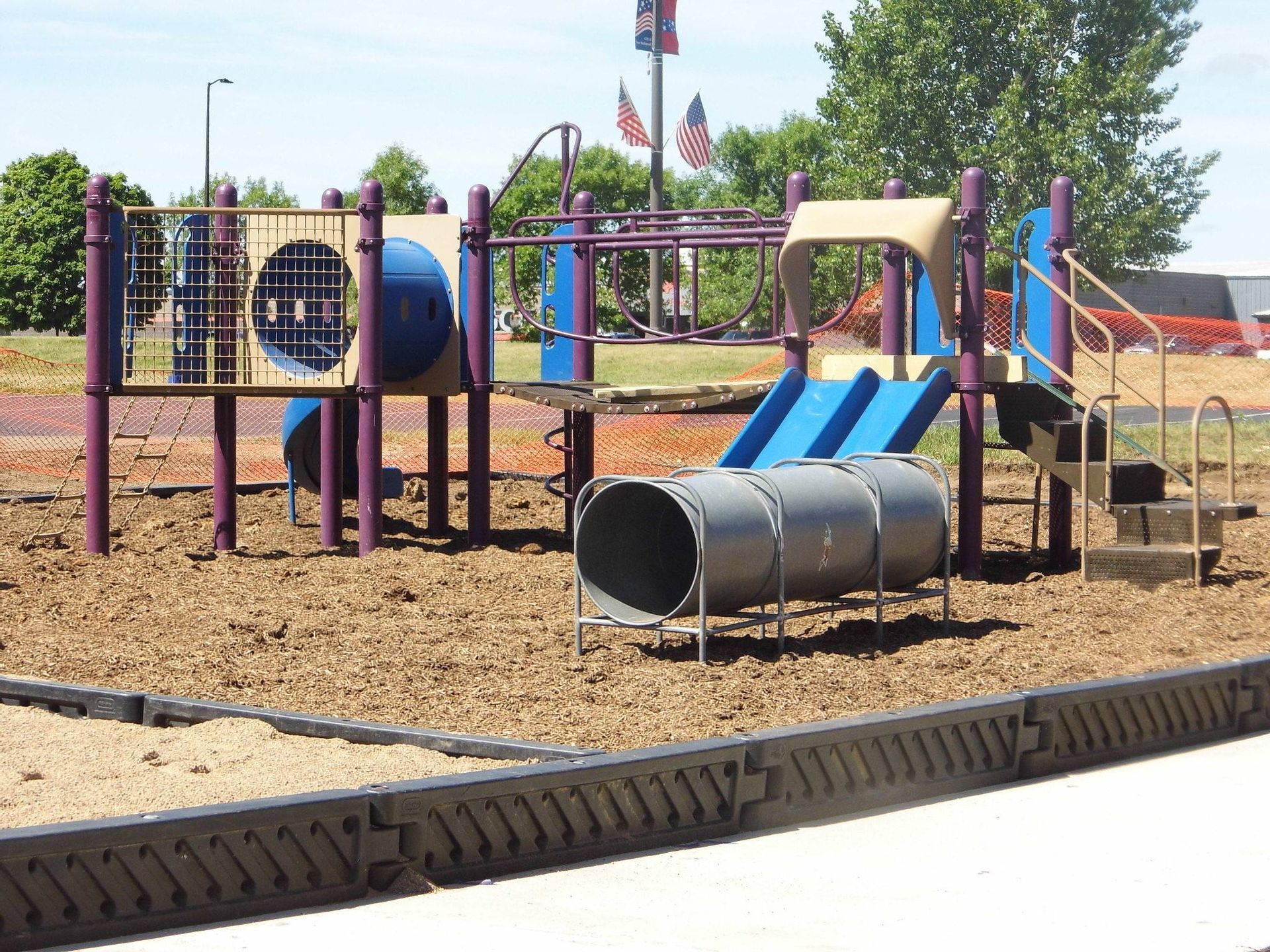 A playground with a blue slide and a purple slide