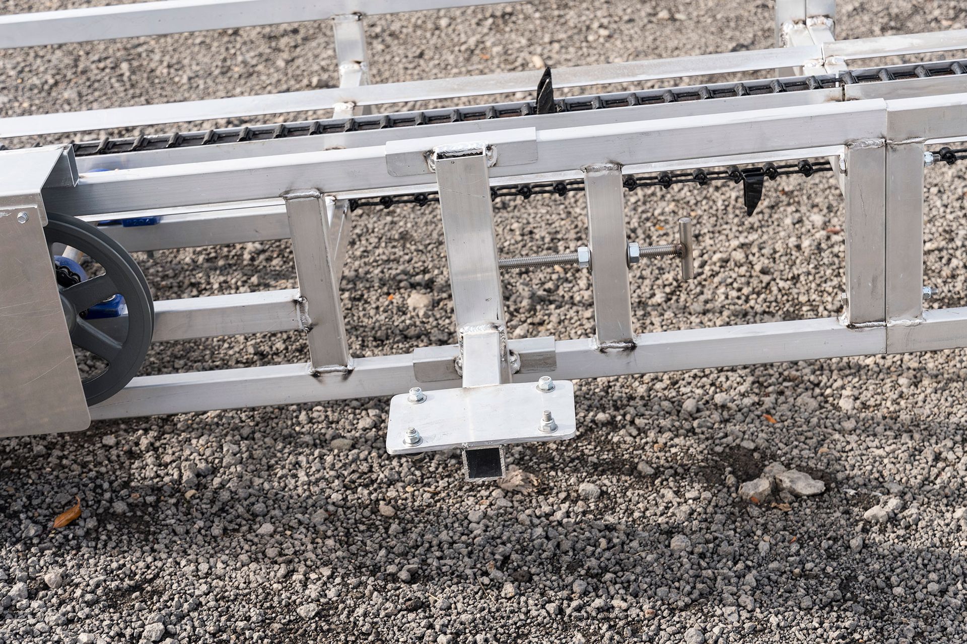 A conveyor belt is sitting on top of a gravel road.