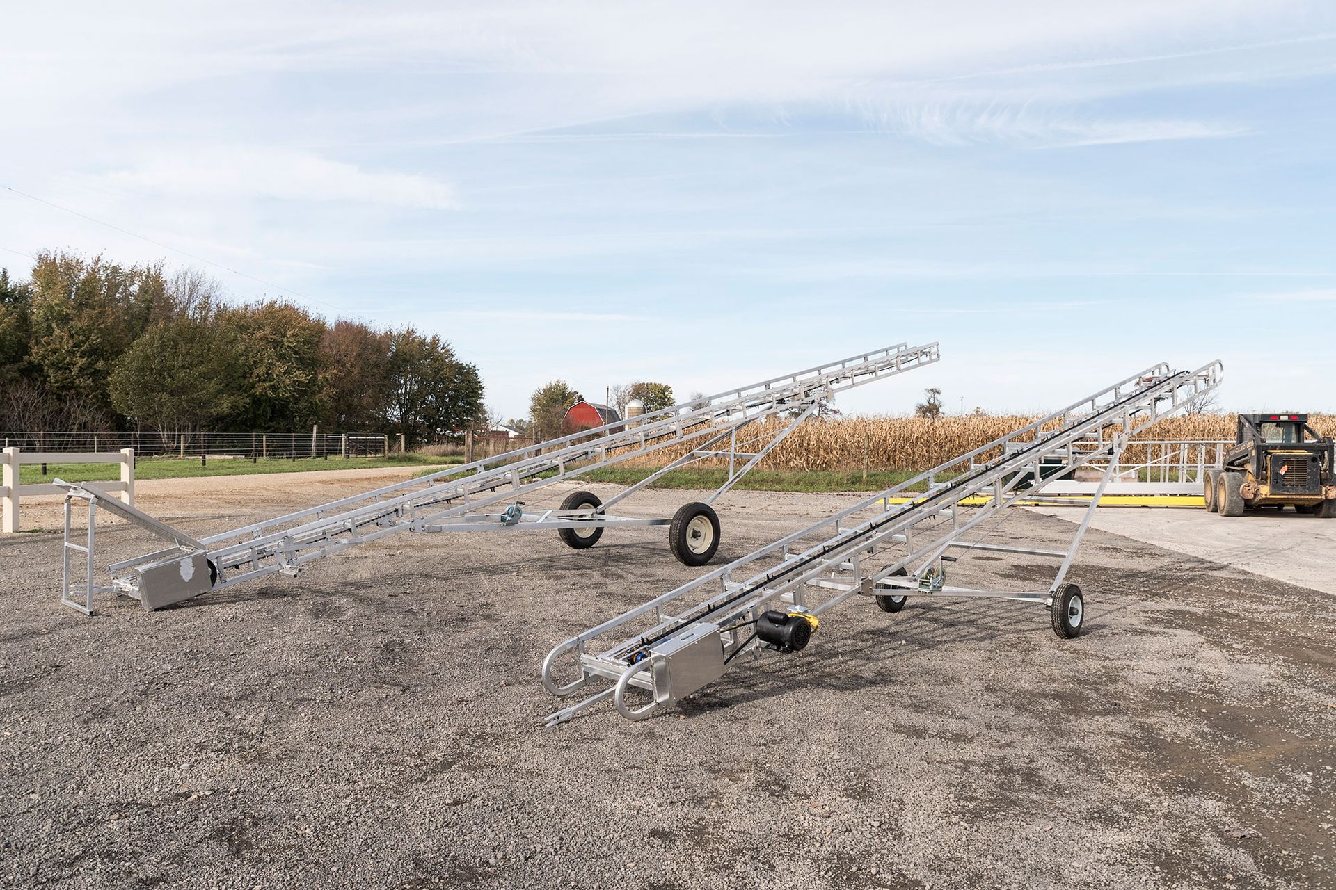 A couple of conveyor belts are sitting on top of a gravel field.