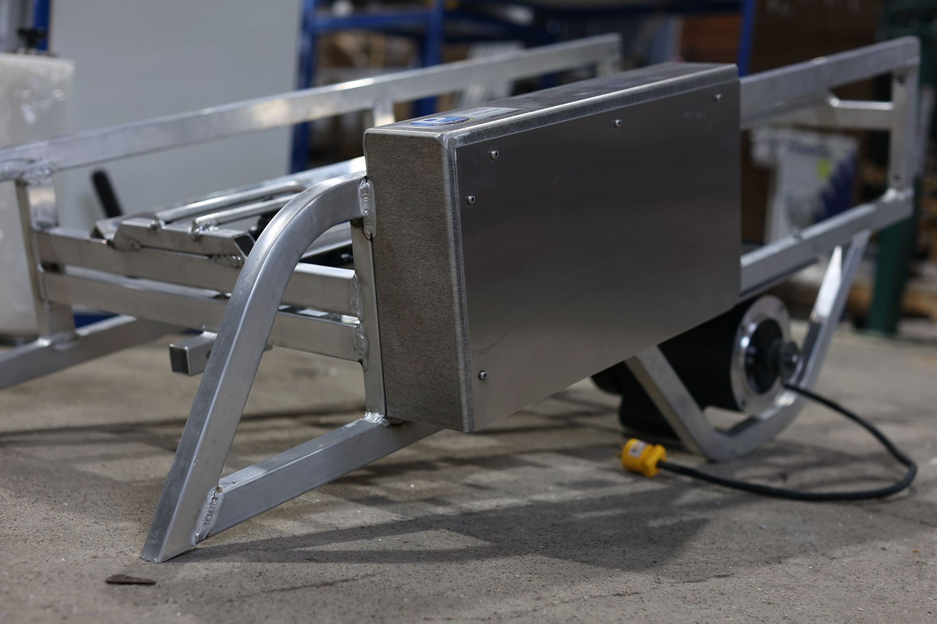 A piece of metal is sitting on the ground with a cord attached to it.