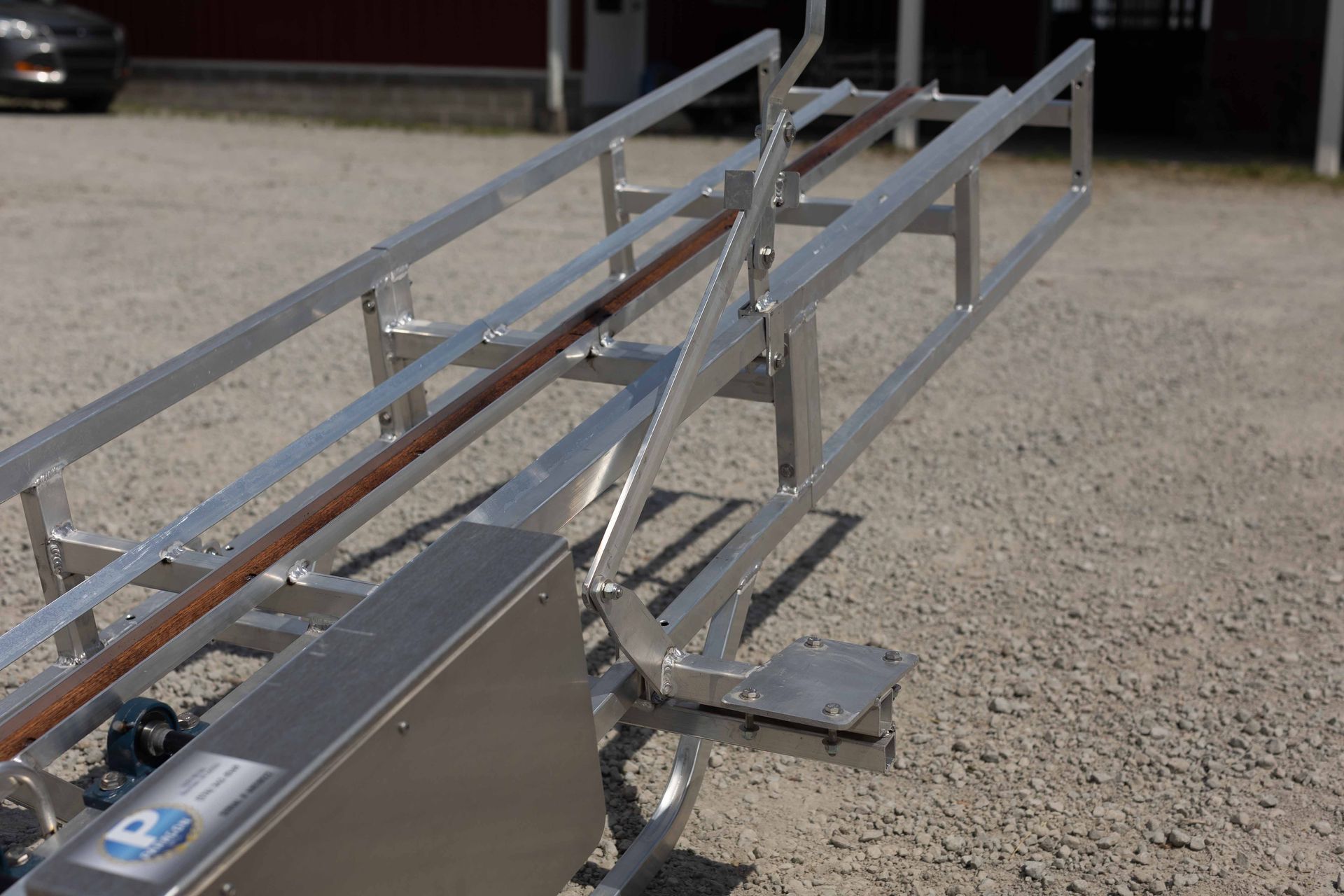 A stainless steel boat trailer is sitting on a gravel road
