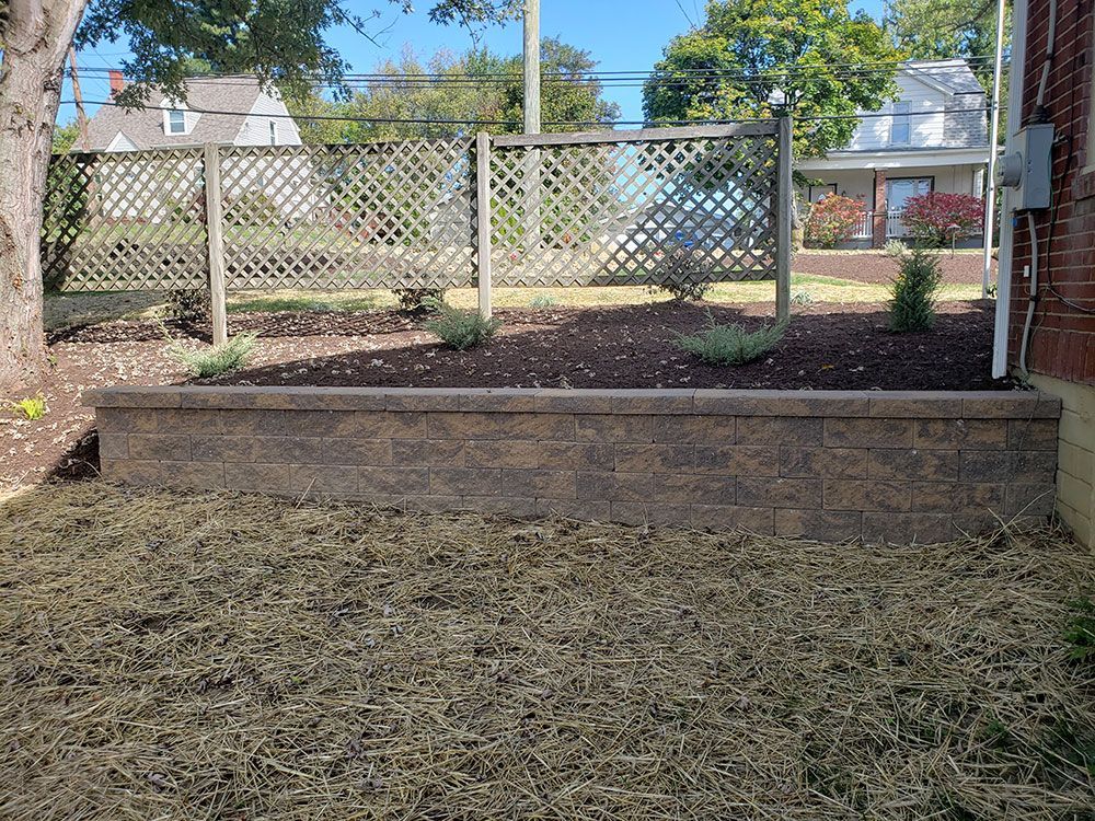 A low retaining wall with a lattice fence holding plants against a residential building.