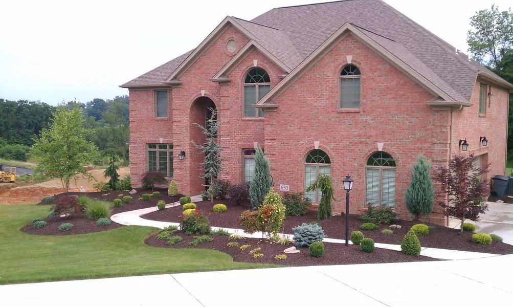 Two-story brick house with landscaped front yard and pathway leading to the front door.
