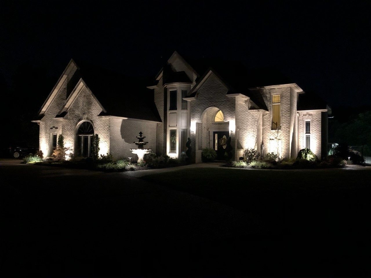 Large stone house illuminated at night with landscape lighting.