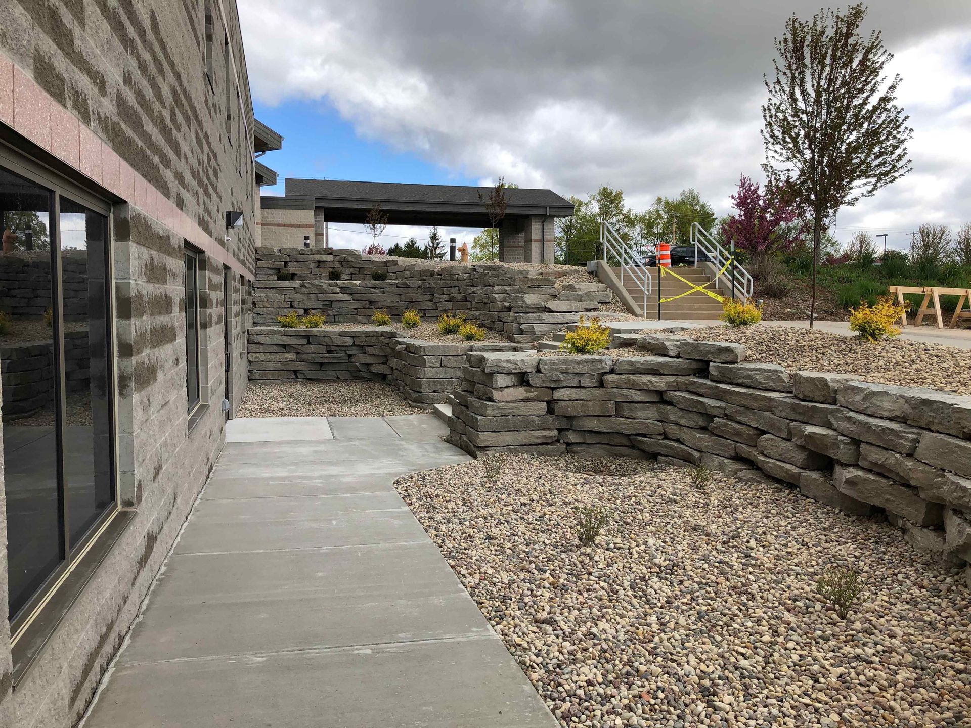 A walkway leading to a building with a stone wall and stairs.