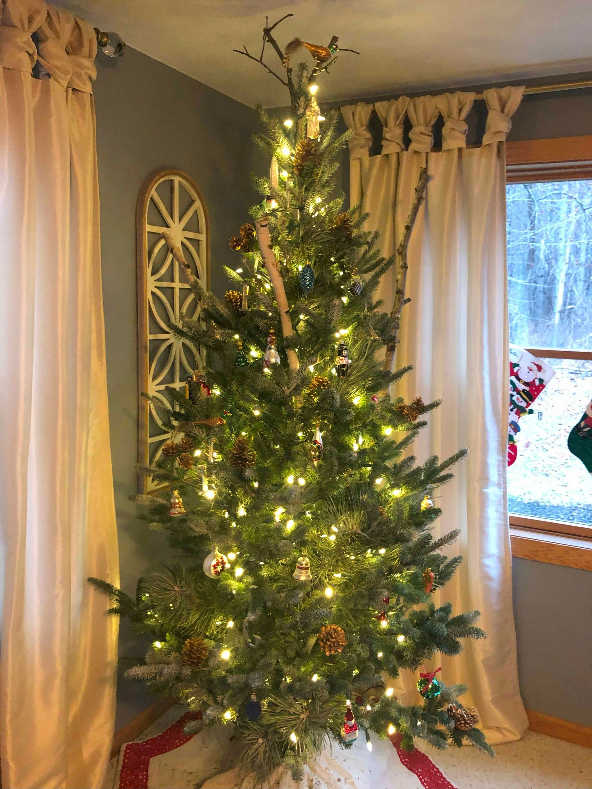 A christmas tree is sitting in a living room next to a window.