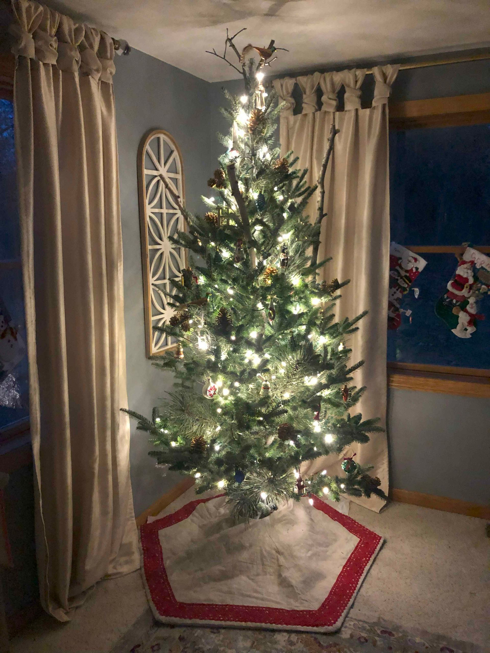 A christmas tree is sitting in a living room next to a window.