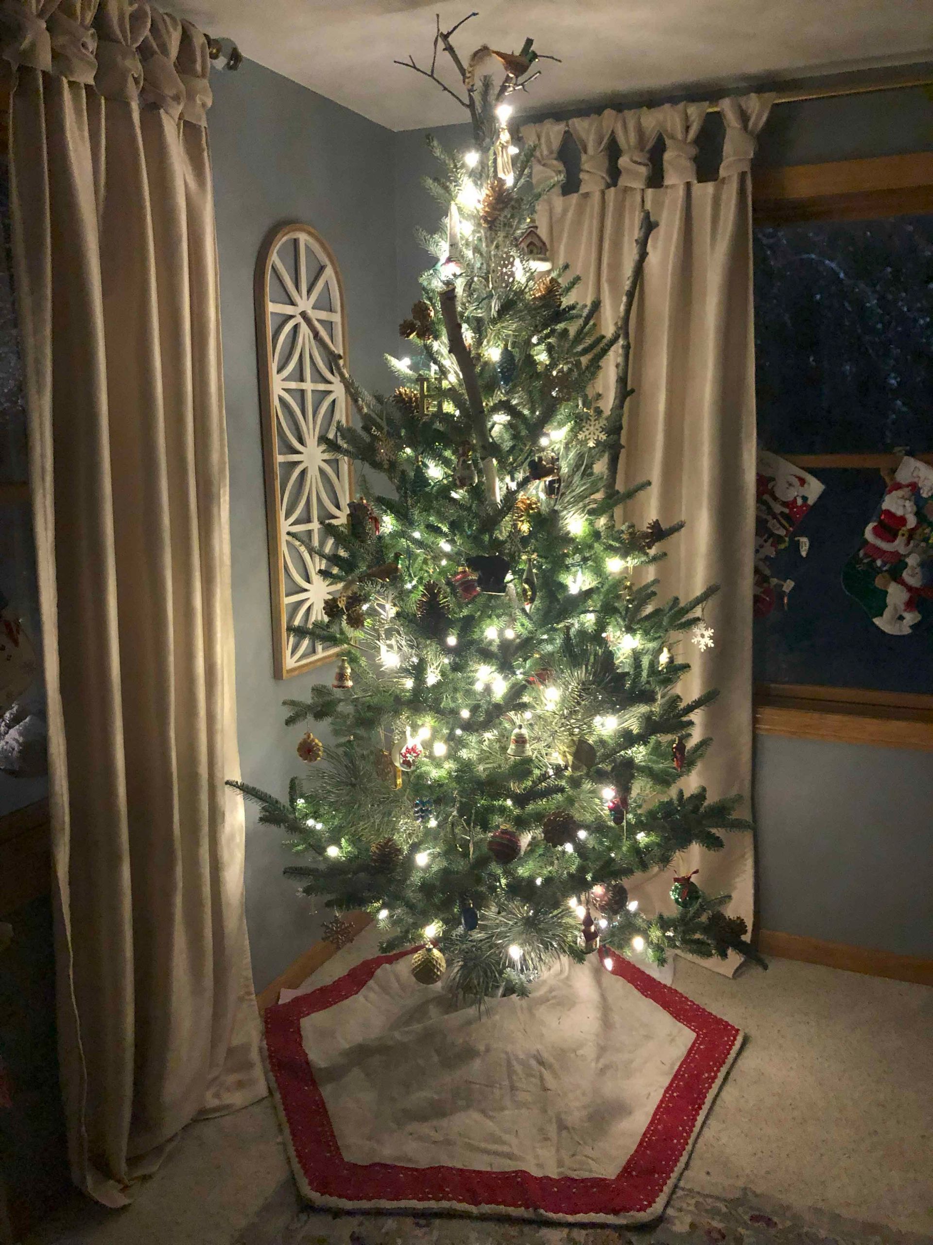 A christmas tree is sitting in a living room next to a window.