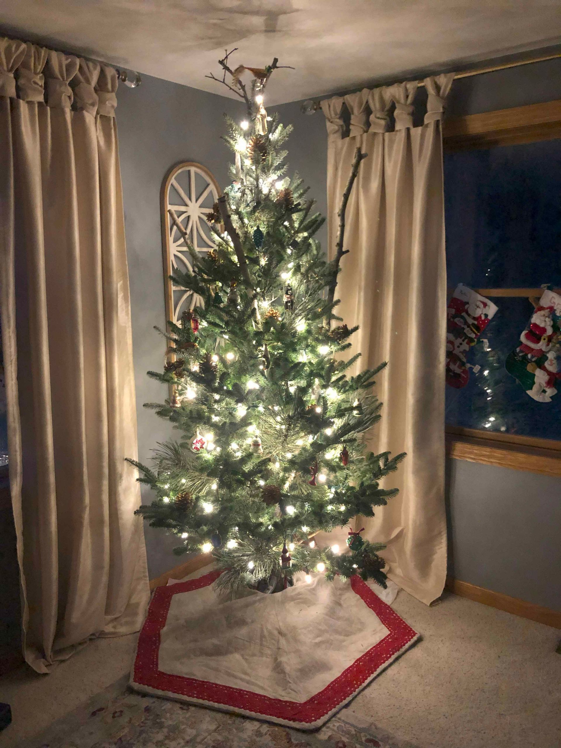 A christmas tree is sitting in a living room next to a window.