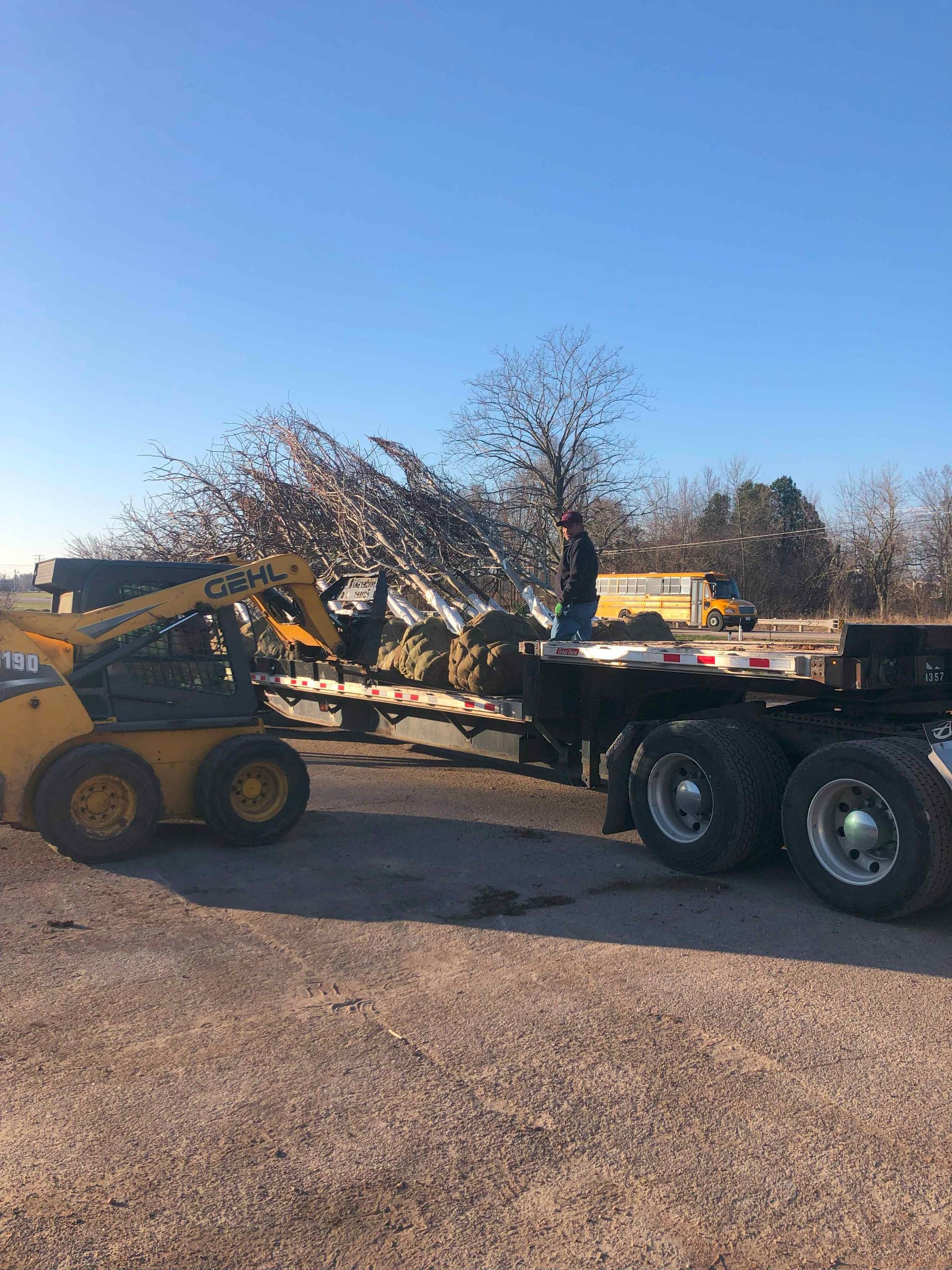 A man is standing on the back of a semi truck.