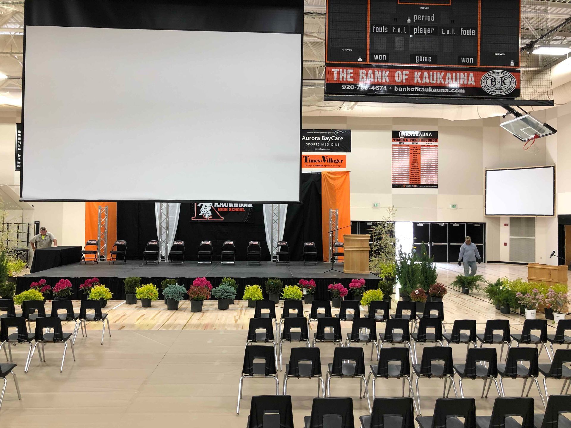 A large auditorium with rows of chairs and a large screen.