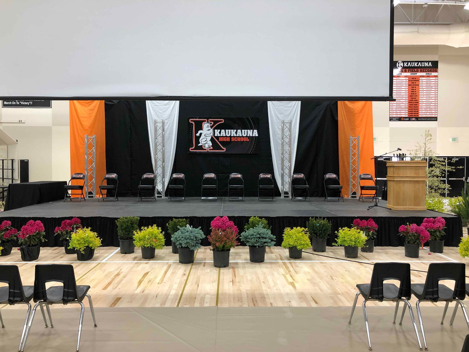 A large stage with flowers and chairs in front of it.
