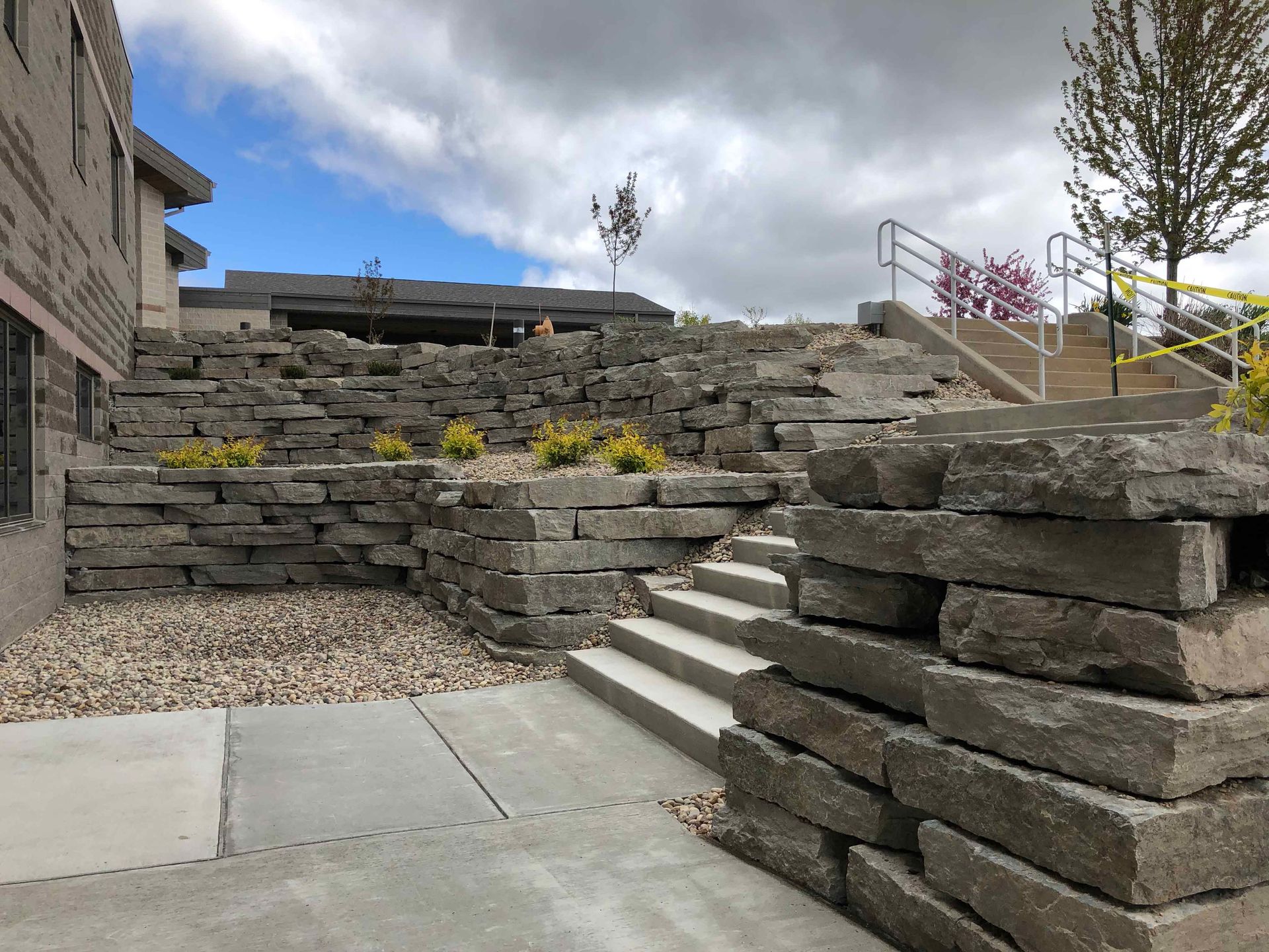 A stone wall with stairs leading up to it and a building in the background.