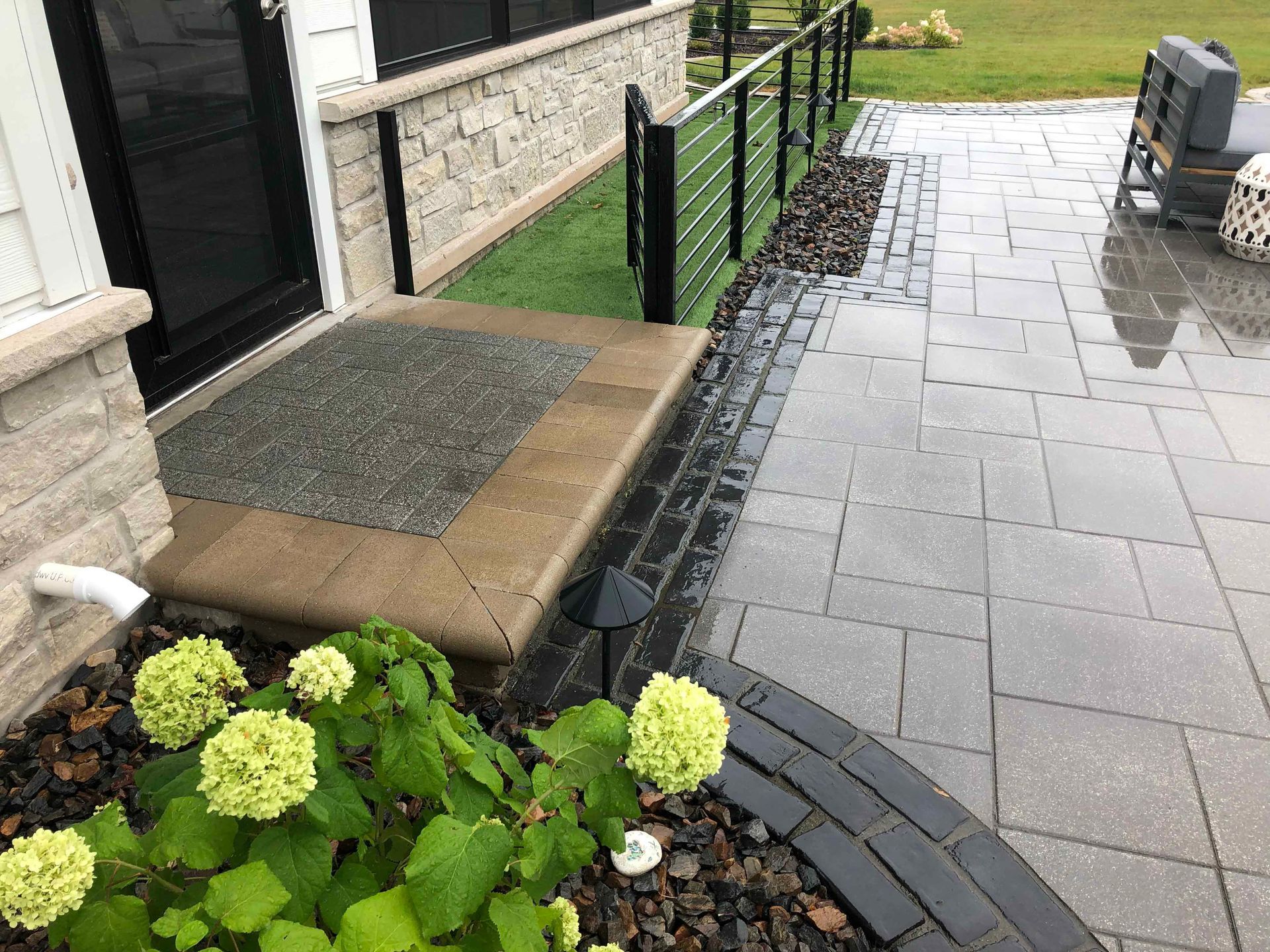 A brick walkway leading to a house with flowers in front of it.