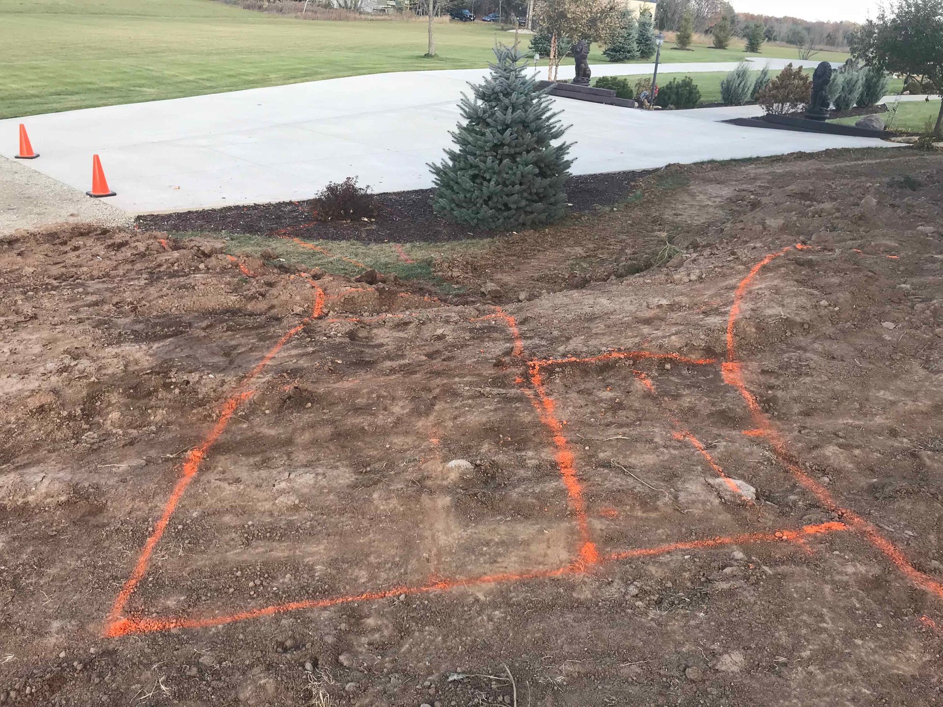 A dirt field with orange lines drawn on it and cones in the background.