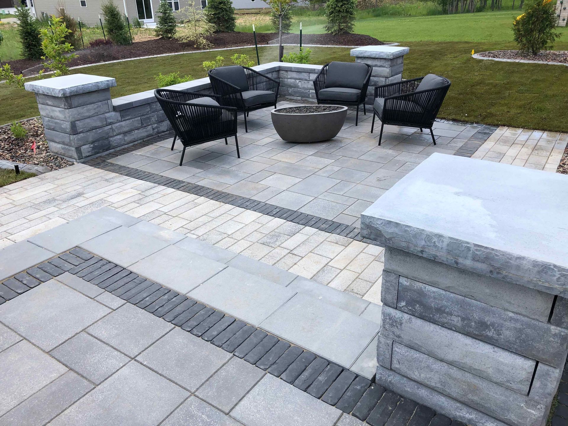 A patio with a fire pit and chairs on it.