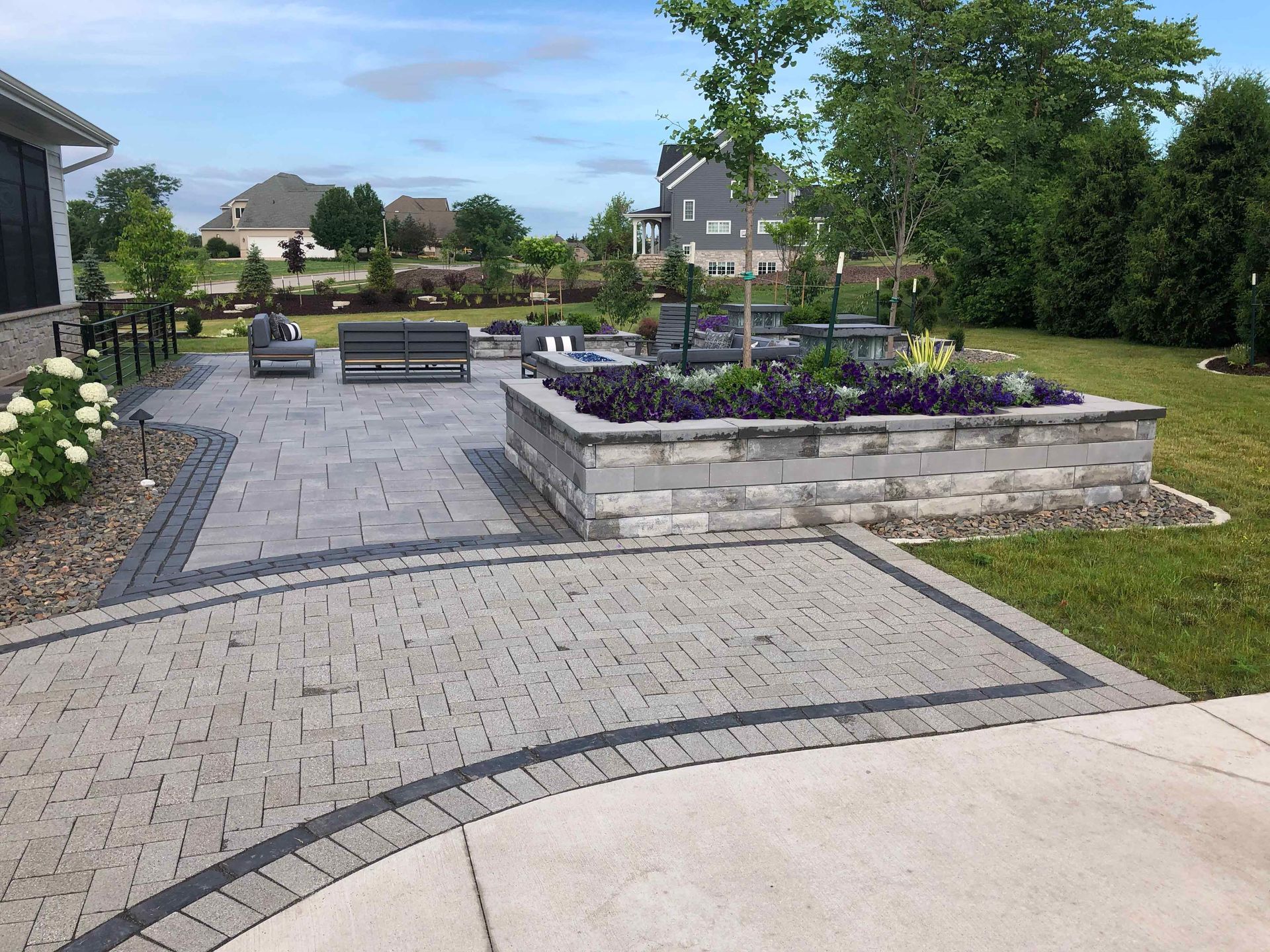 A patio with a brick walkway and a planter in the middle of it.