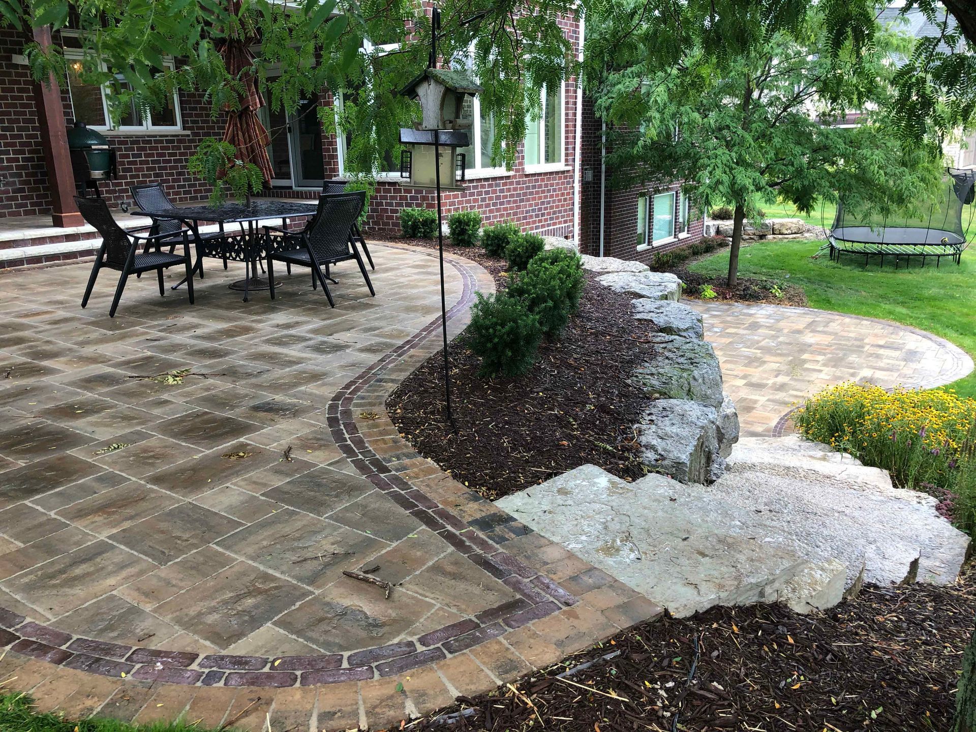 A patio with a table and chairs in front of a brick house.