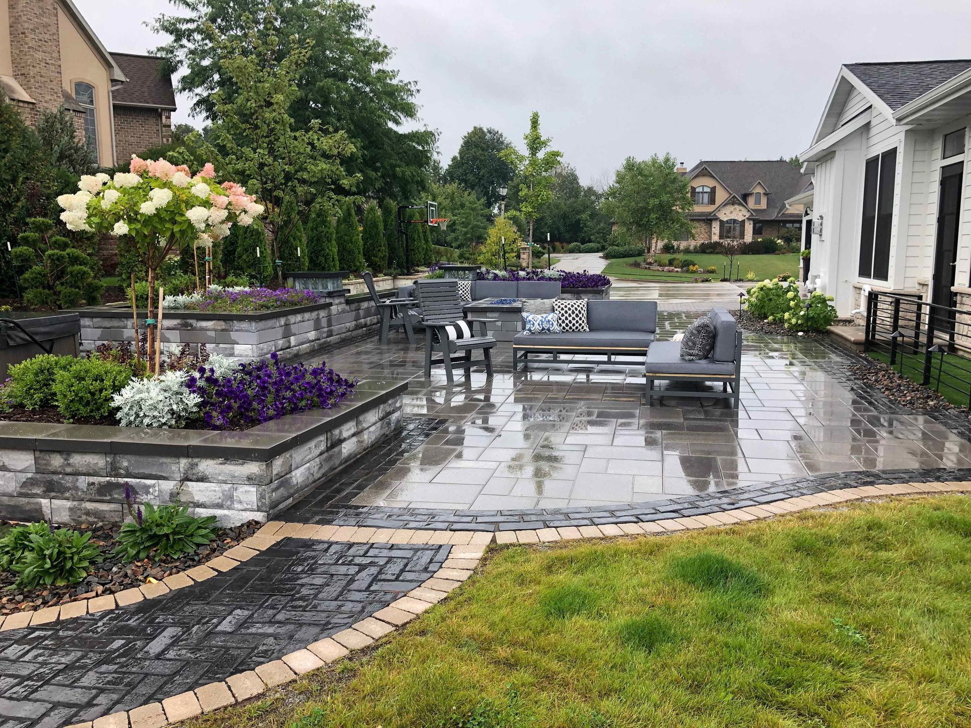 A patio with a lot of furniture and flowers in front of a house.