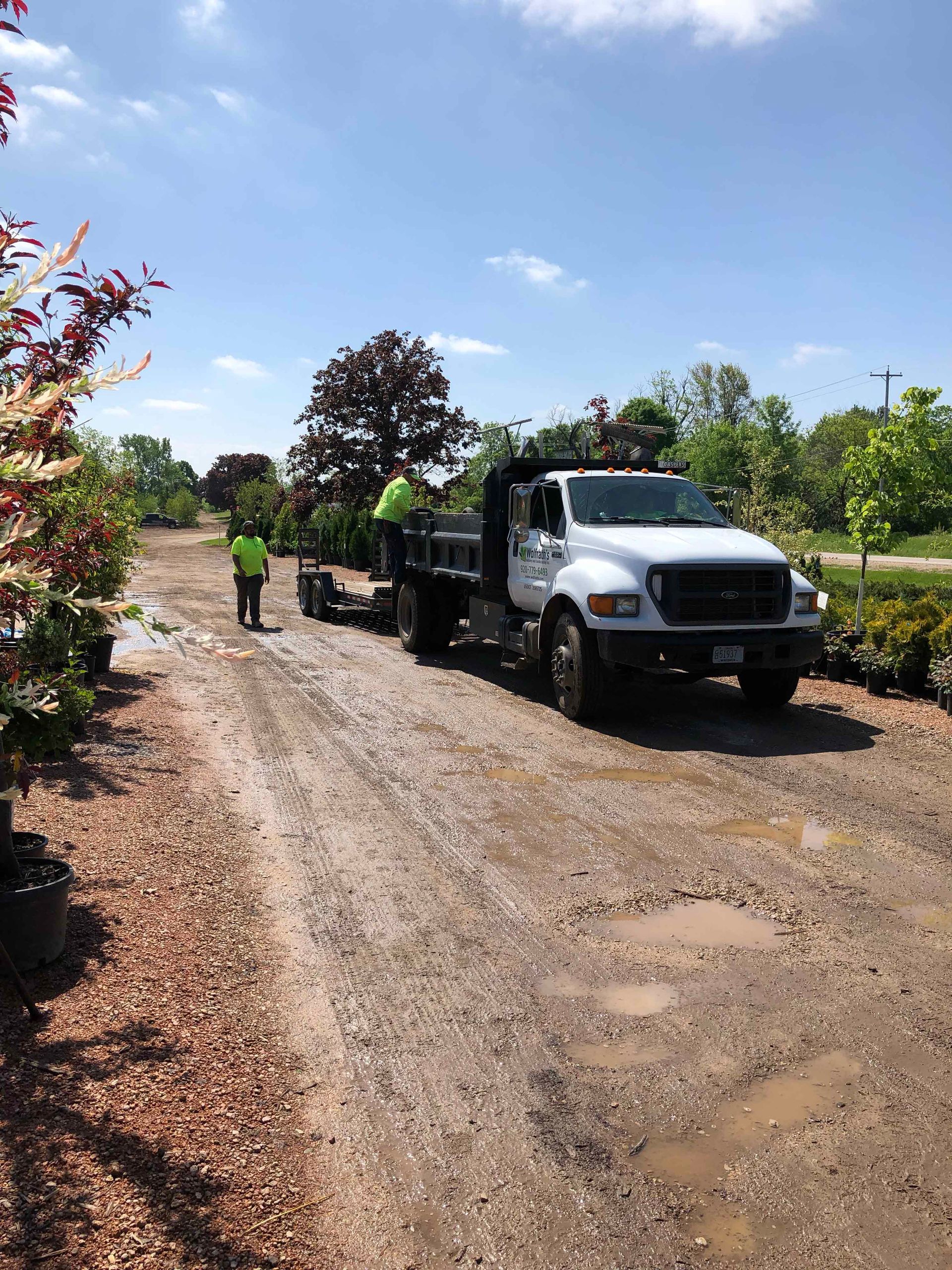 A white truck is parked on the side of a dirt road.