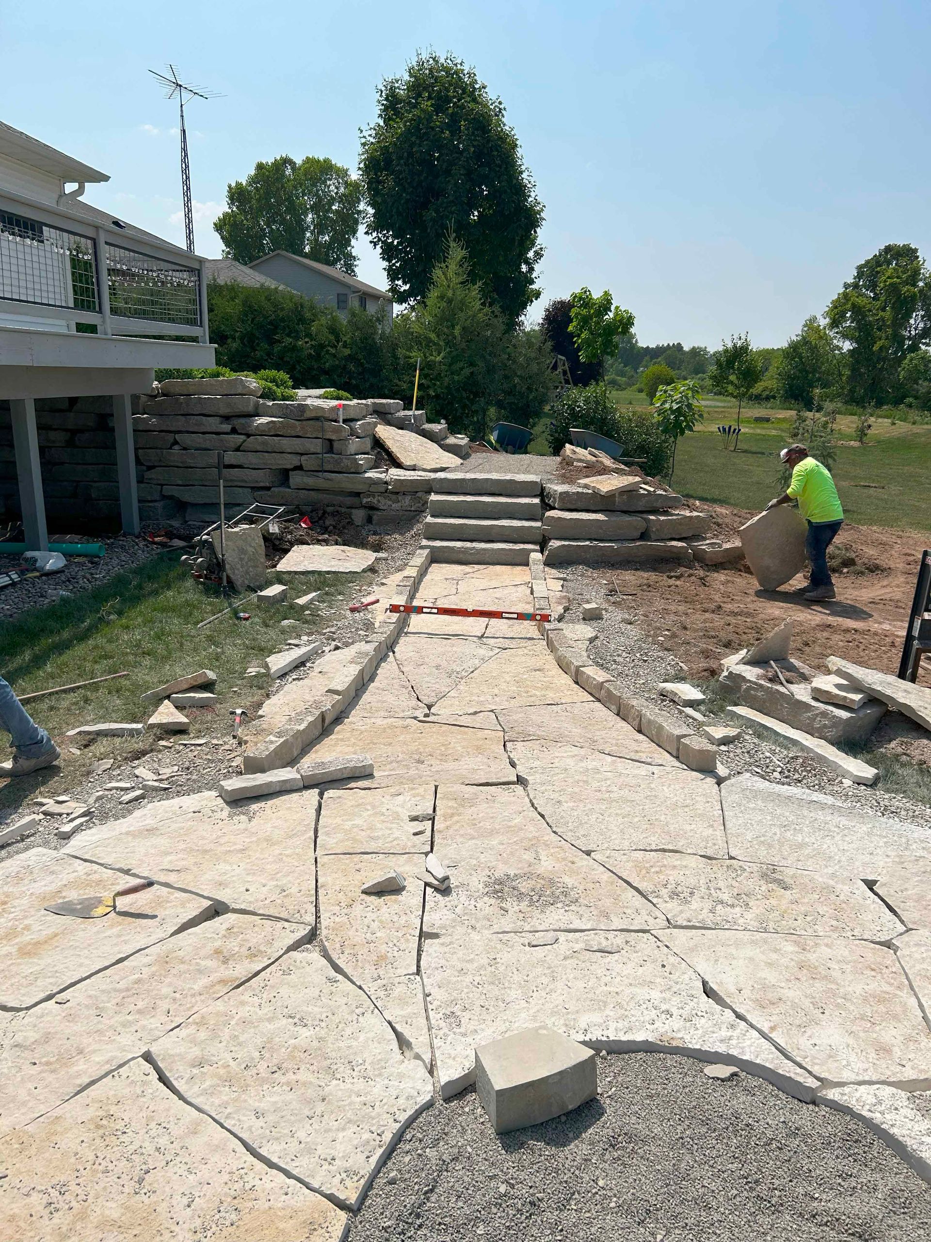 A man is working on a stone walkway in front of a house.