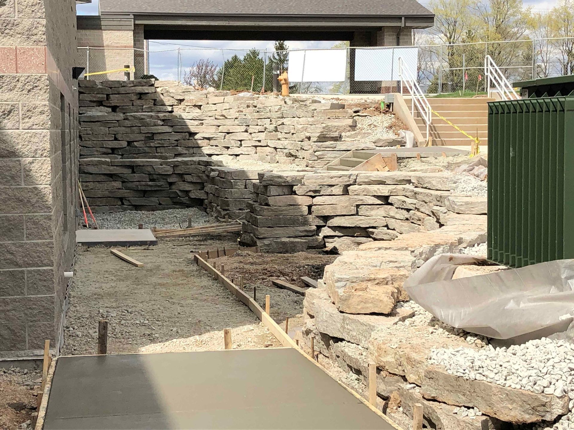 A concrete walkway is being built in front of a stone wall.