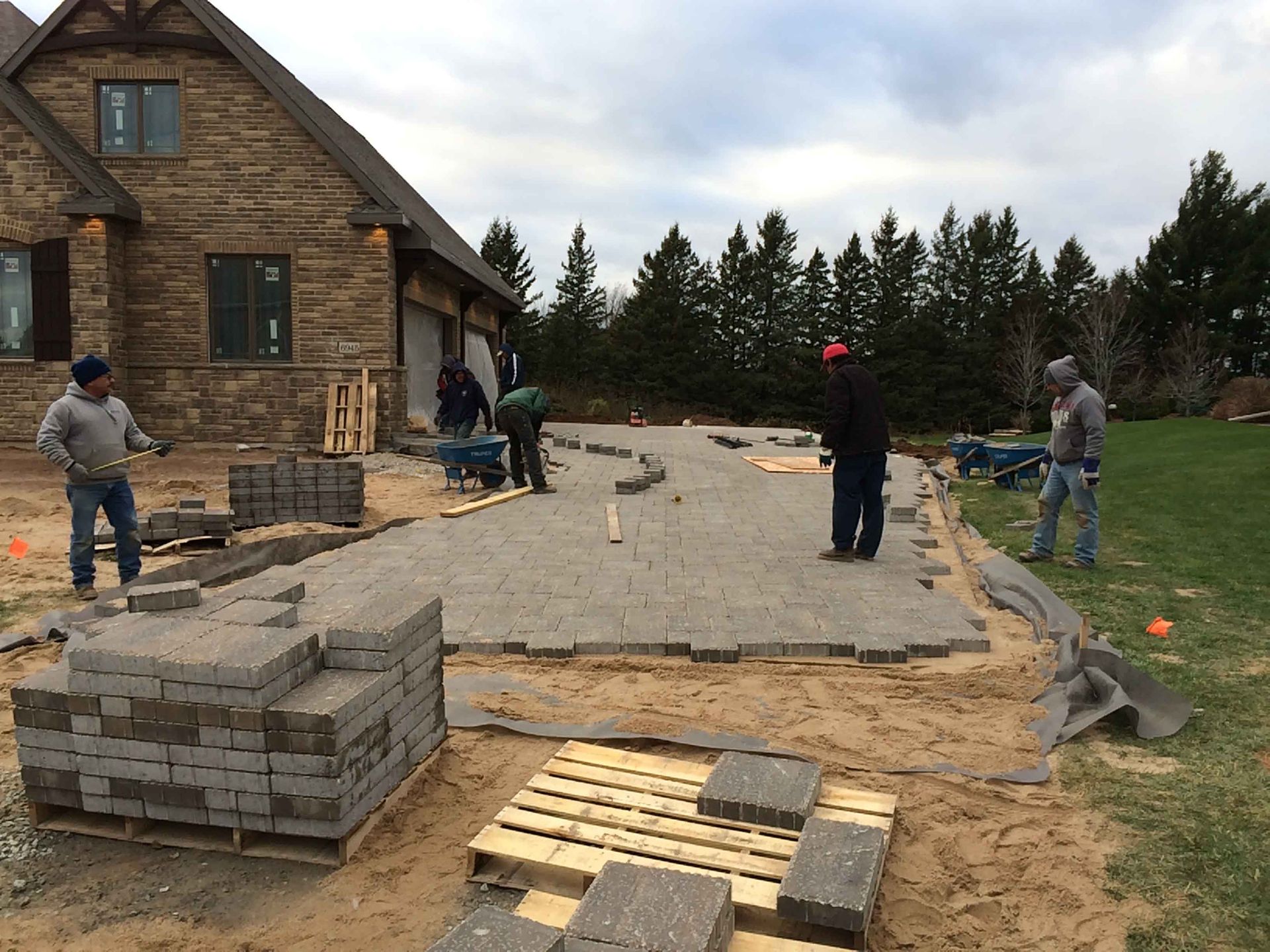 A group of men are working on a driveway in front of a house.