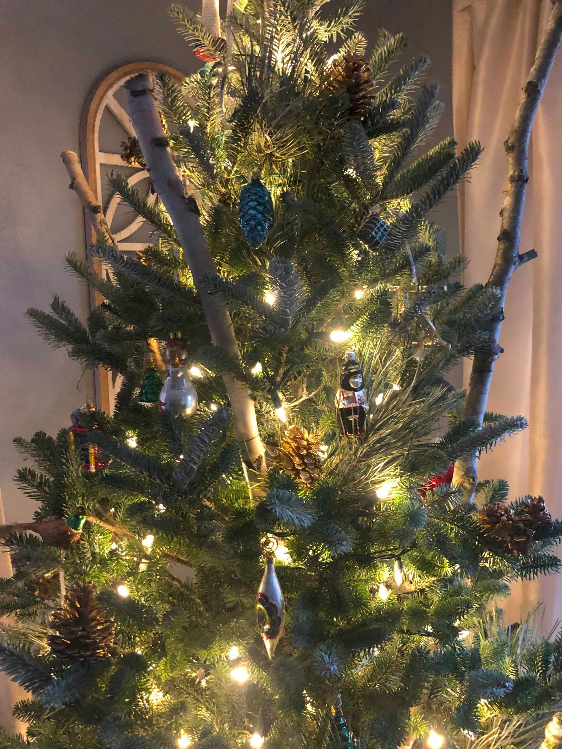 A close up of a christmas tree with lights and decorations in a living room.