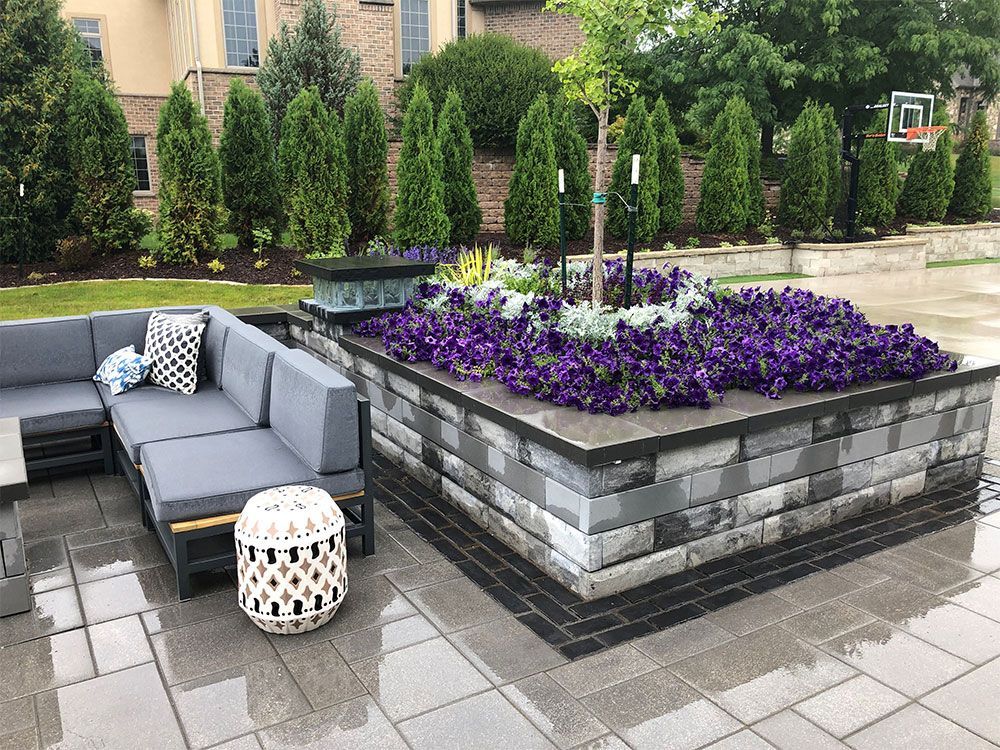 A waterfall in a garden with pumpkins and flowers.