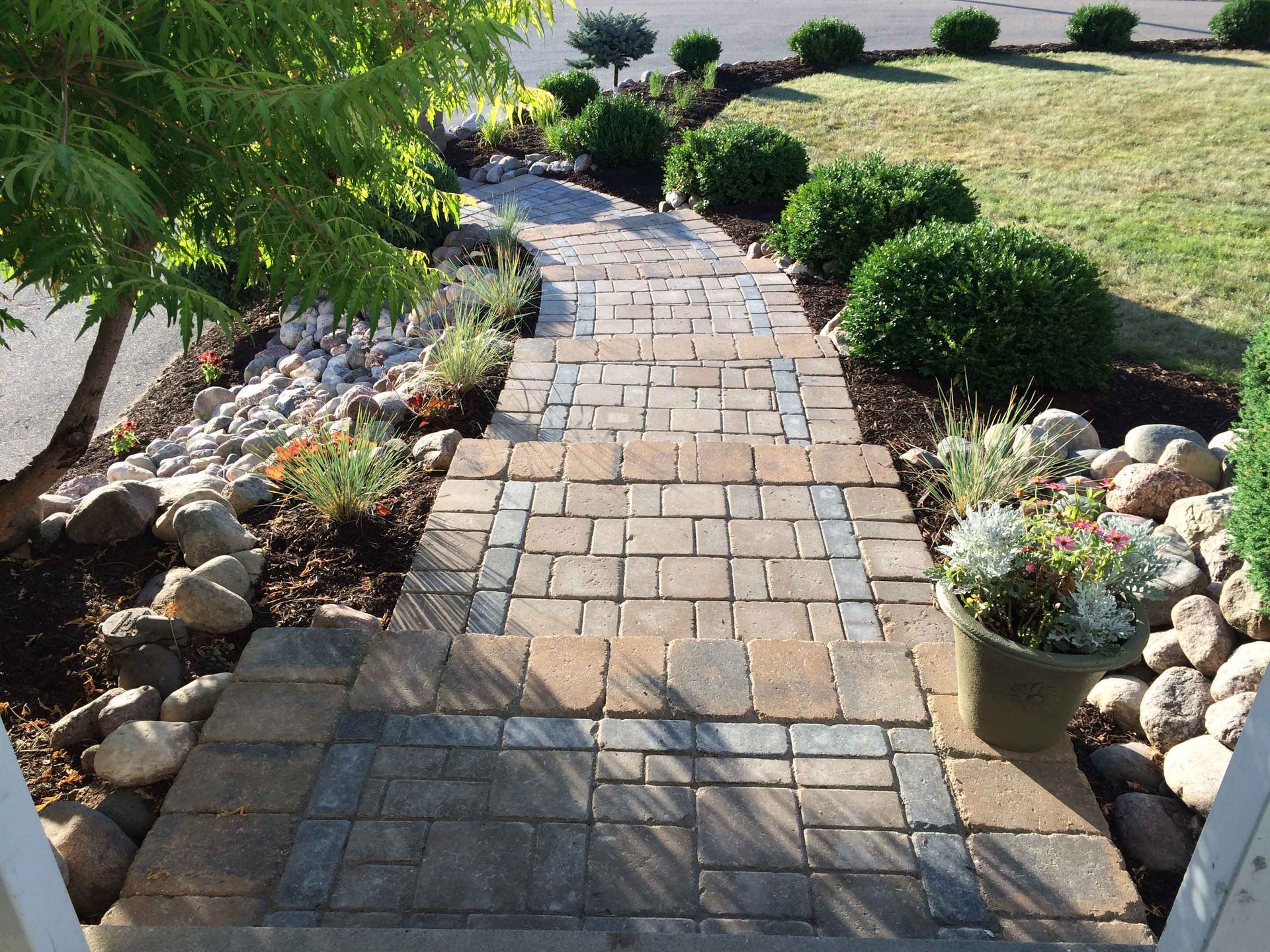 A brick walkway leading to a lush green yard