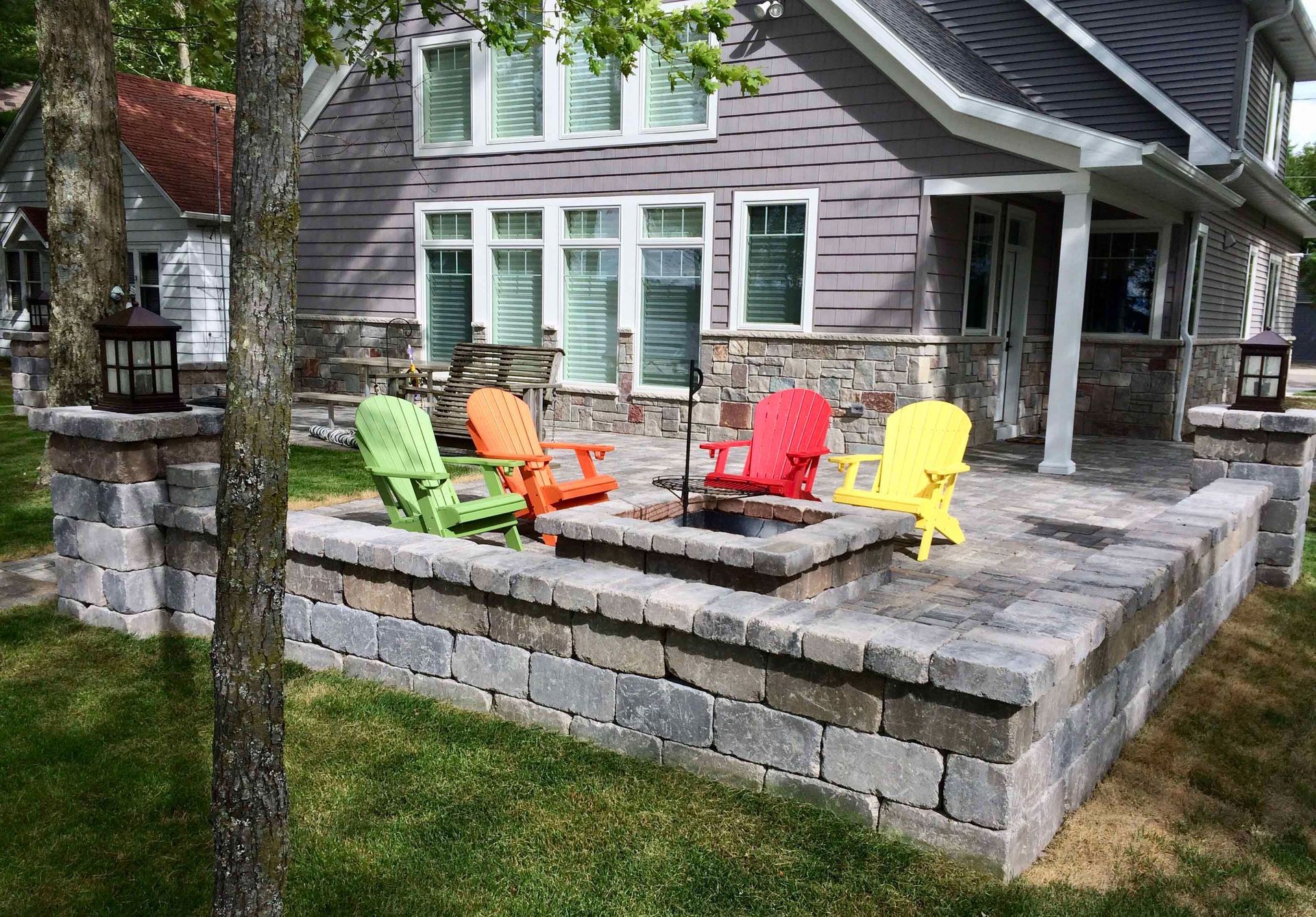 A patio with a fire pit and chairs in front of a house.