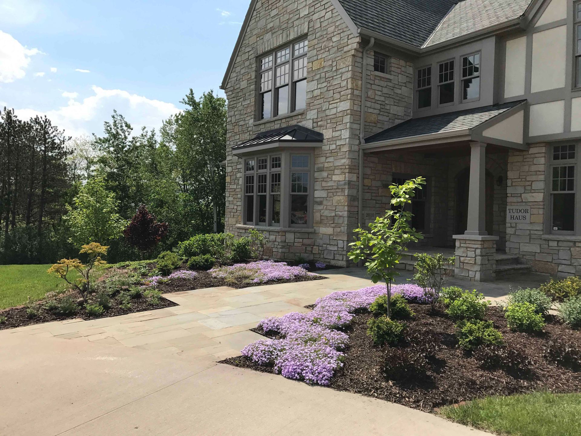 A large stone house with purple flowers in front of it.