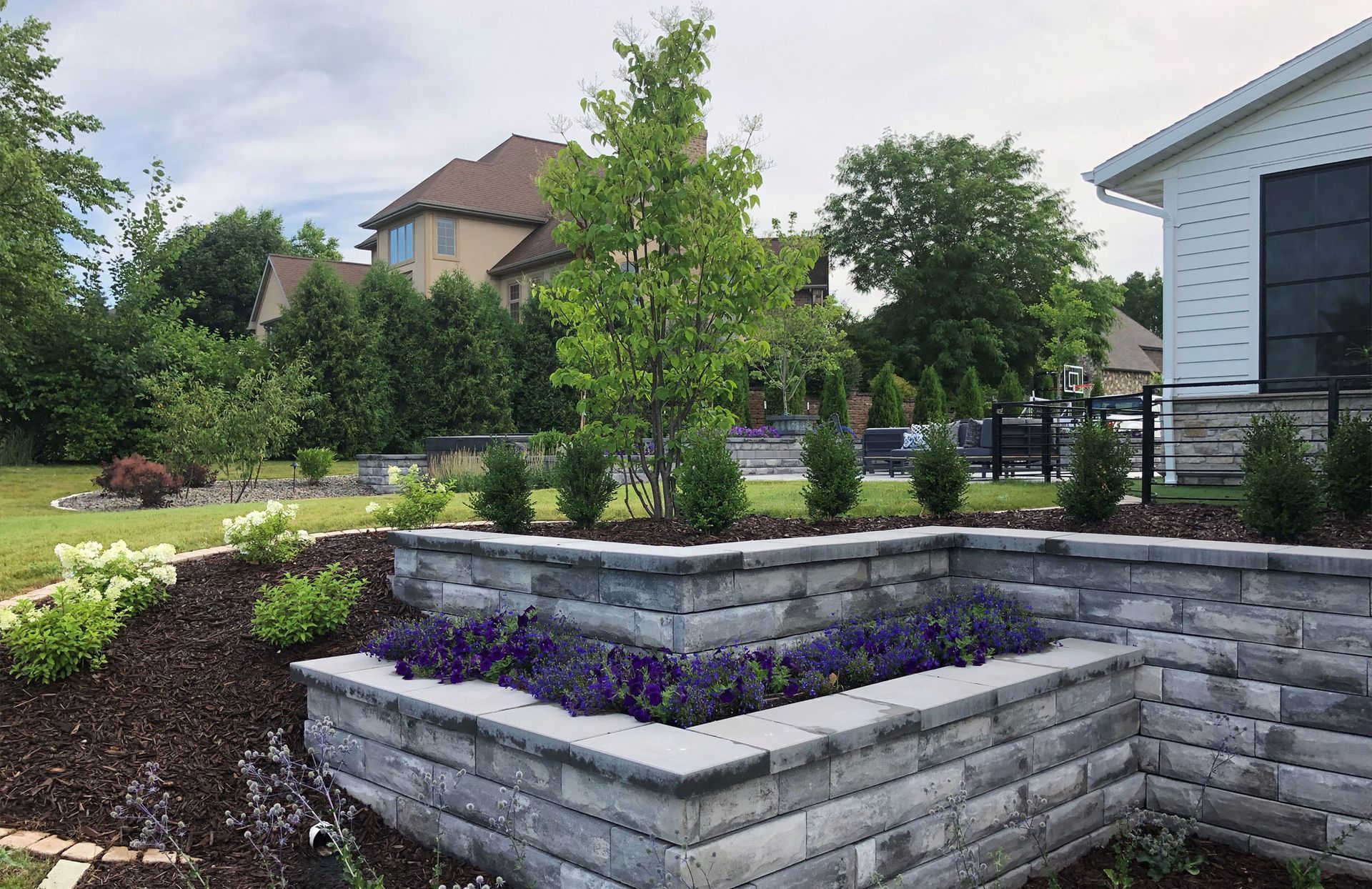 A brick wall with flowers in it in front of a house.