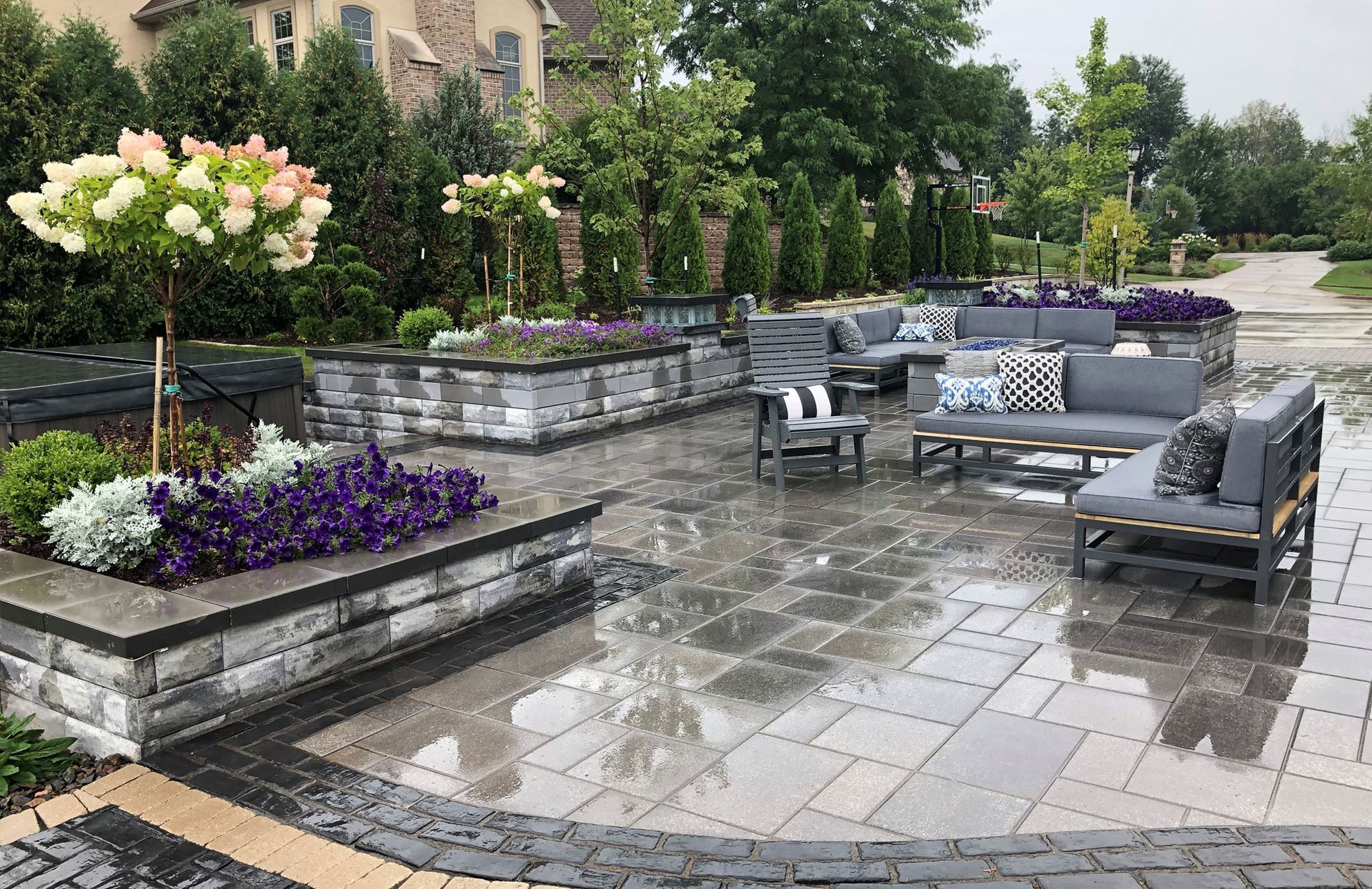 A patio with a lot of furniture and flowers in the rain.