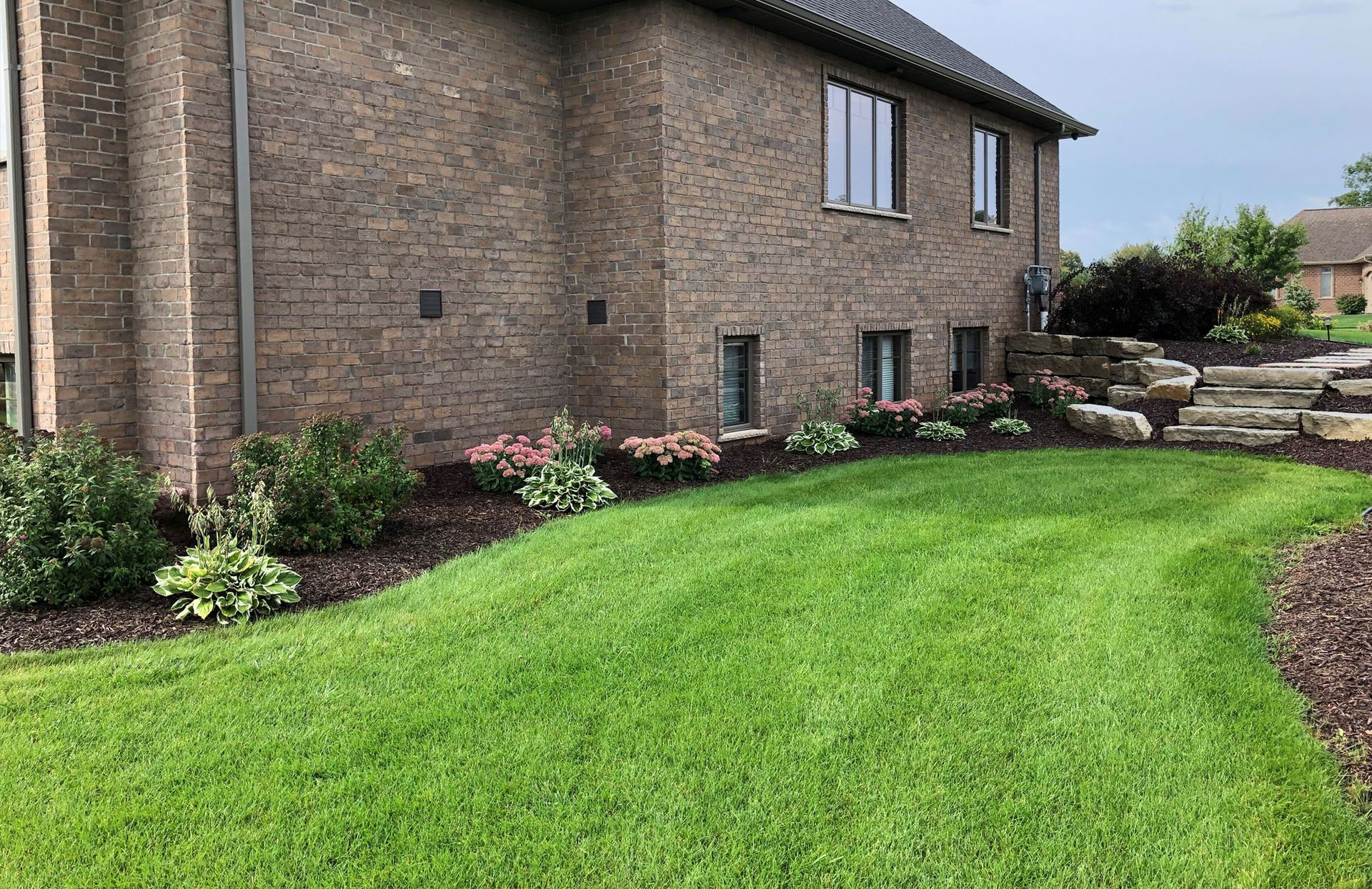 A large brick house with a lush green lawn in front of it.