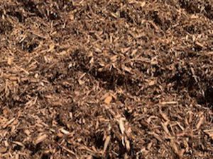 A pile of brown mulch is sitting on the ground.
