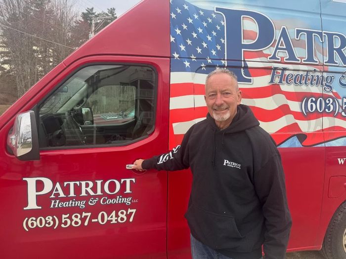 Man standing beside a red Patriot Heating & Cooling van with a U.S. flag graphic.