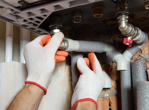 A person wearing gloves is working on a pipe