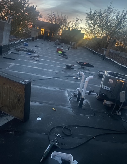 a roof with a lot of pipes on it and a building in the background
